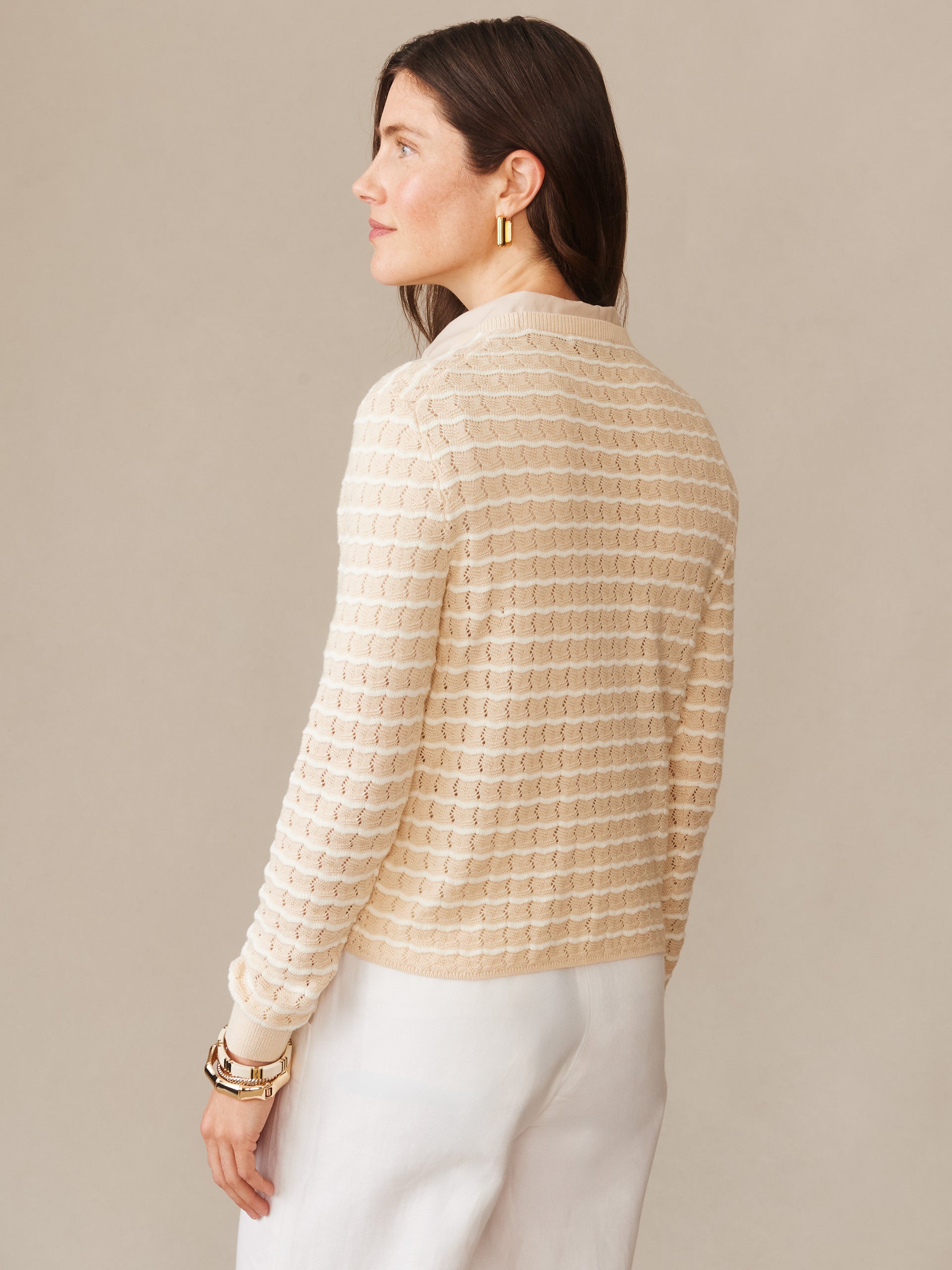 A woman wearing the Brenna Sweater in Stripe by J.McLaughlin in a soft oatmeal and off-white pattern, showcasing effortlessly stylish and enduring designs in timeless fashion.