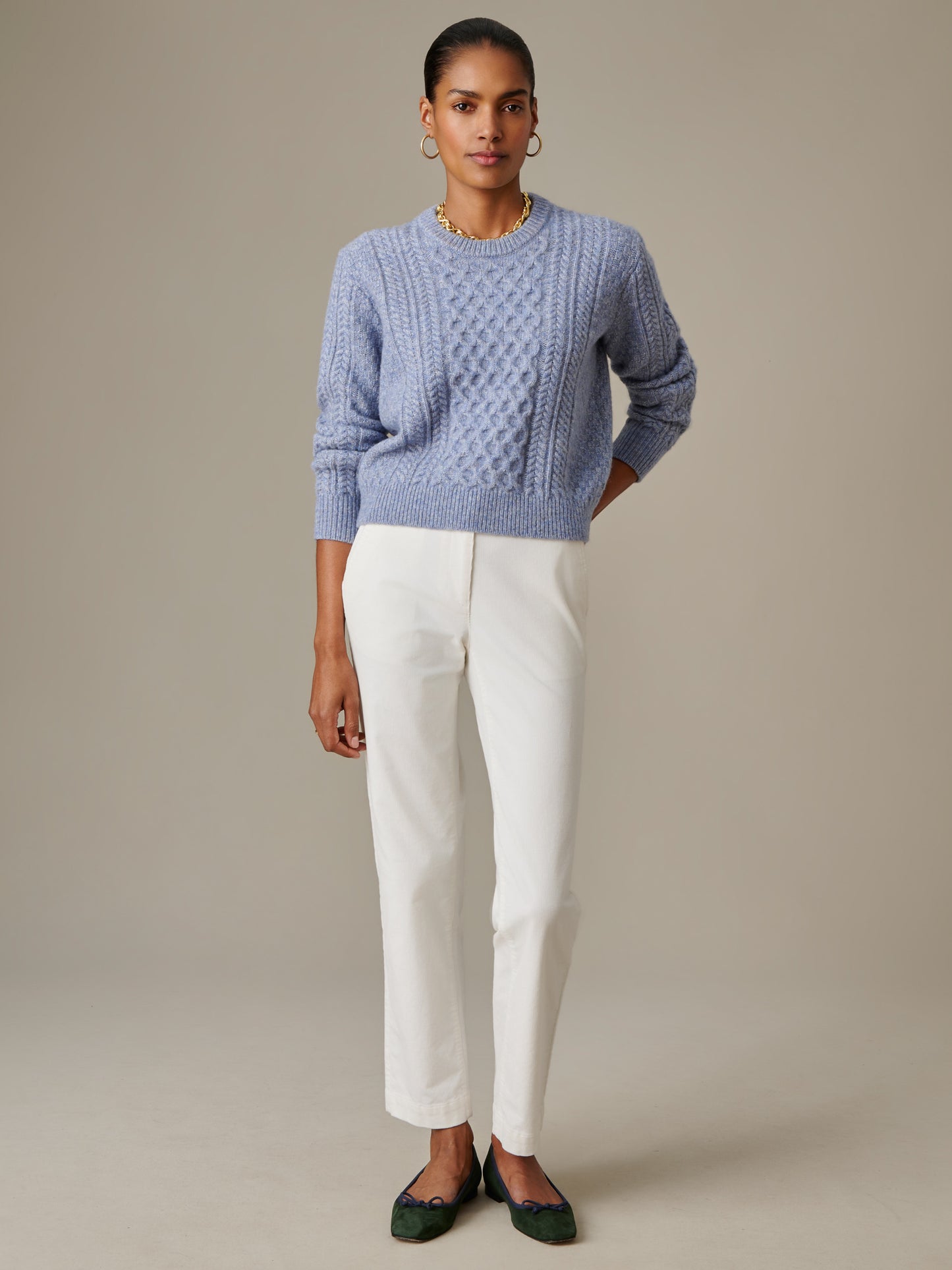 Woman wearing a light blue Brigette Sweater by J.McLaughlin with textured knit design, paired with white pants and green flats, showcasing enduring style and craftsmanship.