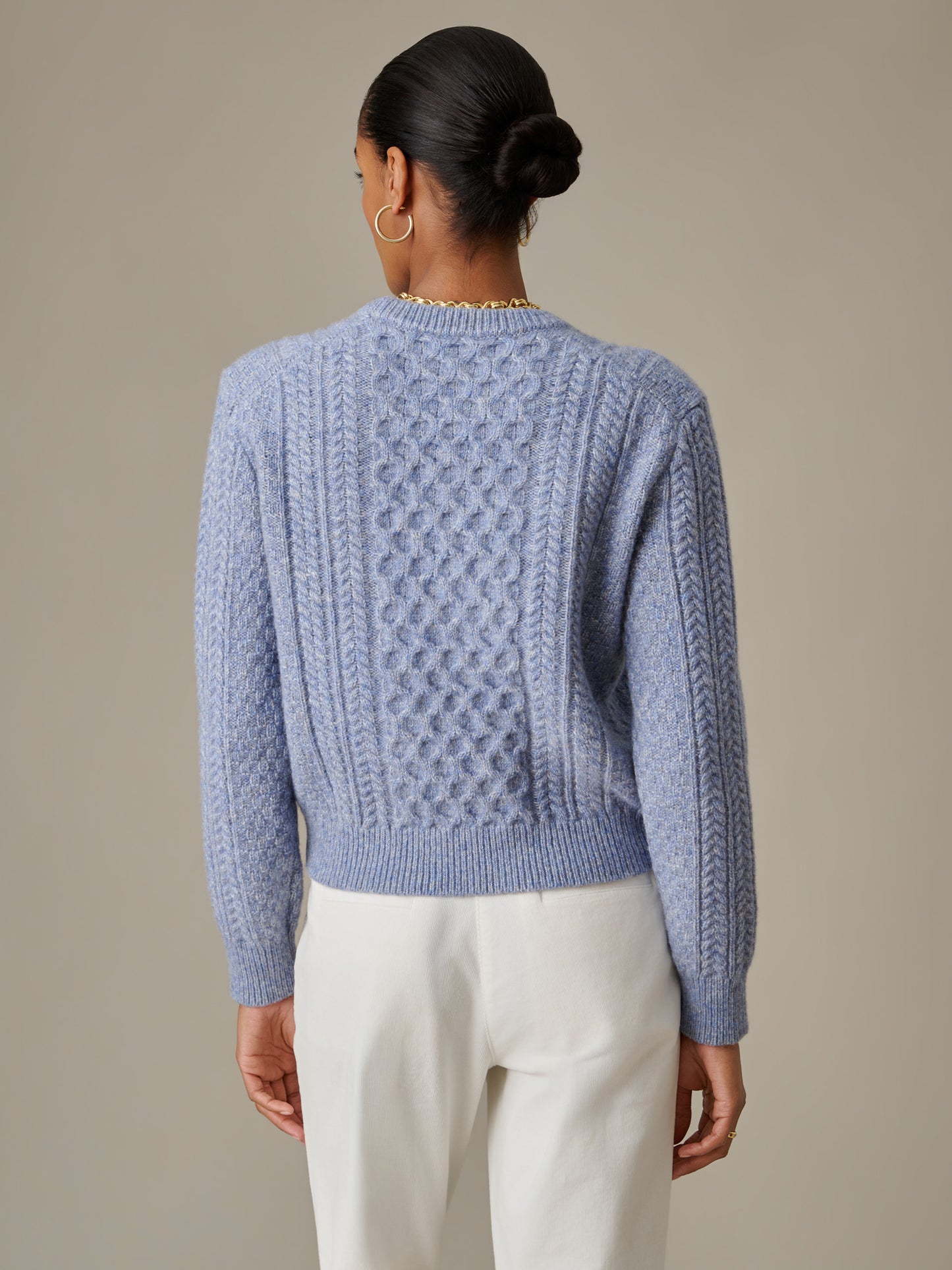 Woman wearing a light blue Brigette Sweater by J.McLaughlin featuring textured cable knit design, paired with white pants, displaying timeless style and craftsmanship.