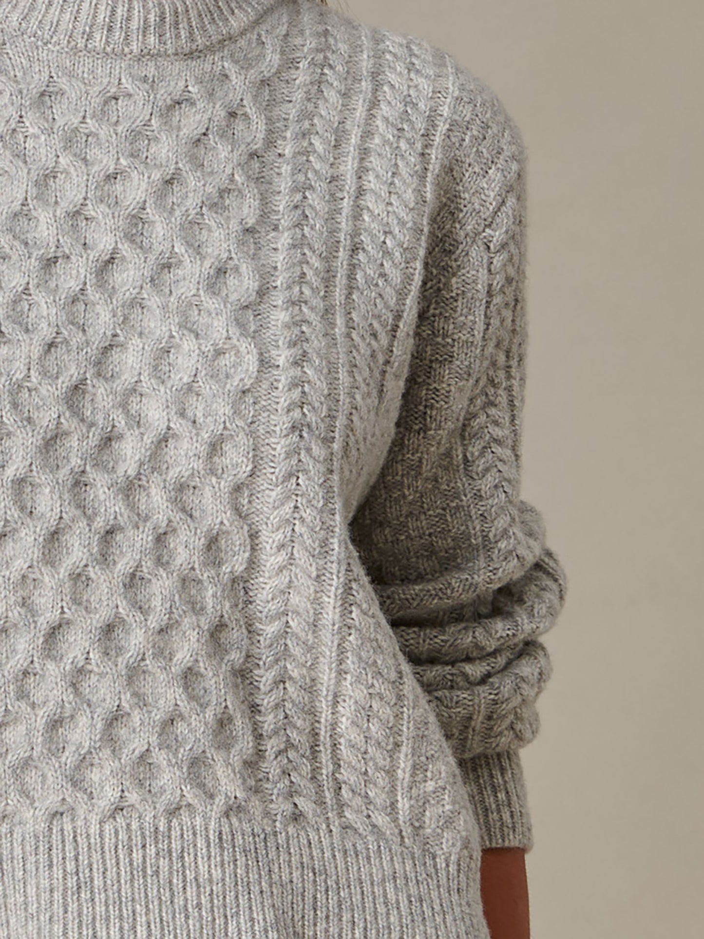 Close-up of a cozy grey cable-knit Brigette Sweater by J.McLaughlin, showcasing intricate craftsmanship and enduring timeless style for comfortable, stylish layering.