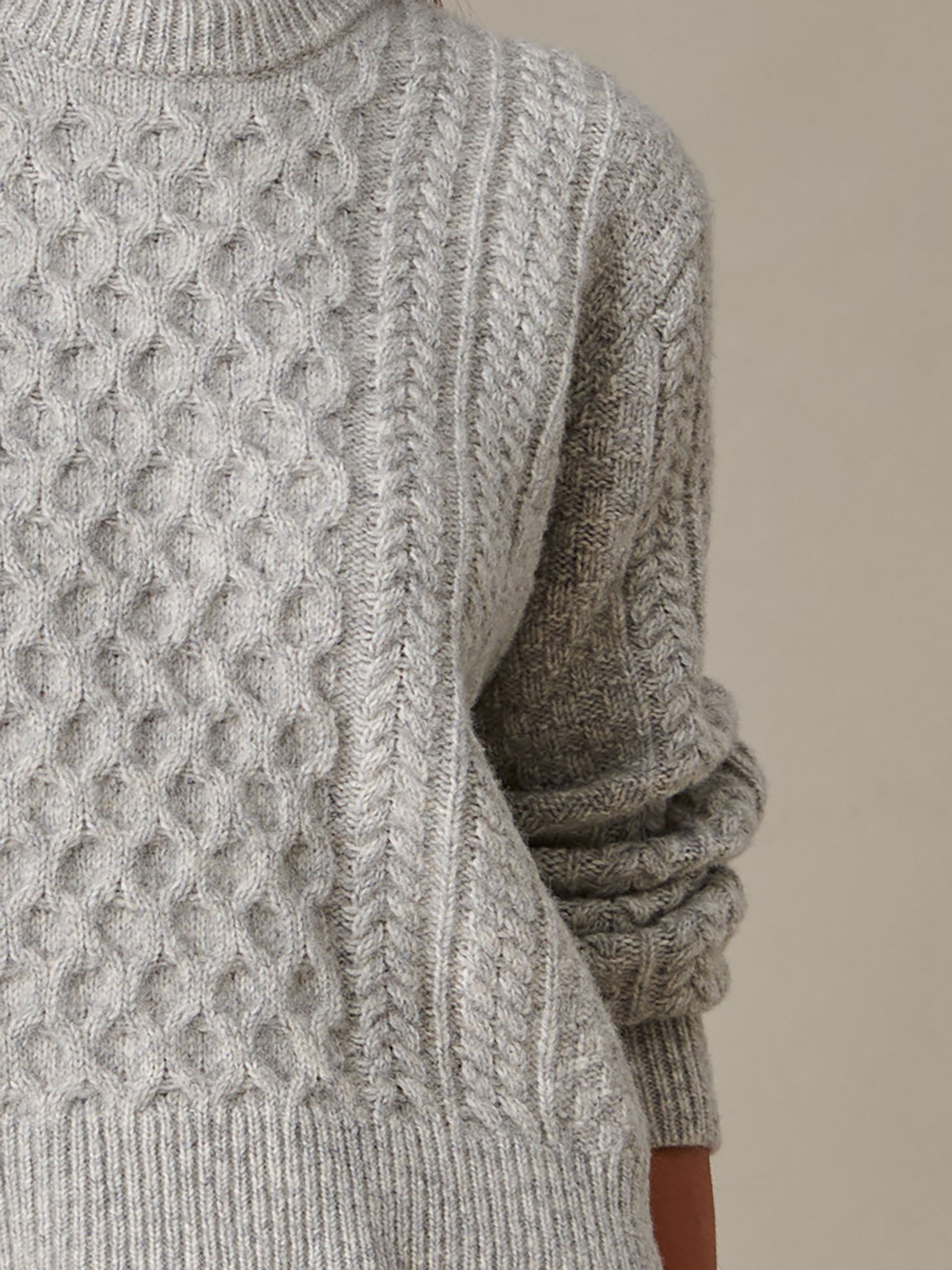 Close-up of a cozy grey cable-knit Brigette Sweater by J.McLaughlin, showcasing intricate craftsmanship and enduring timeless style for comfortable, stylish layering.