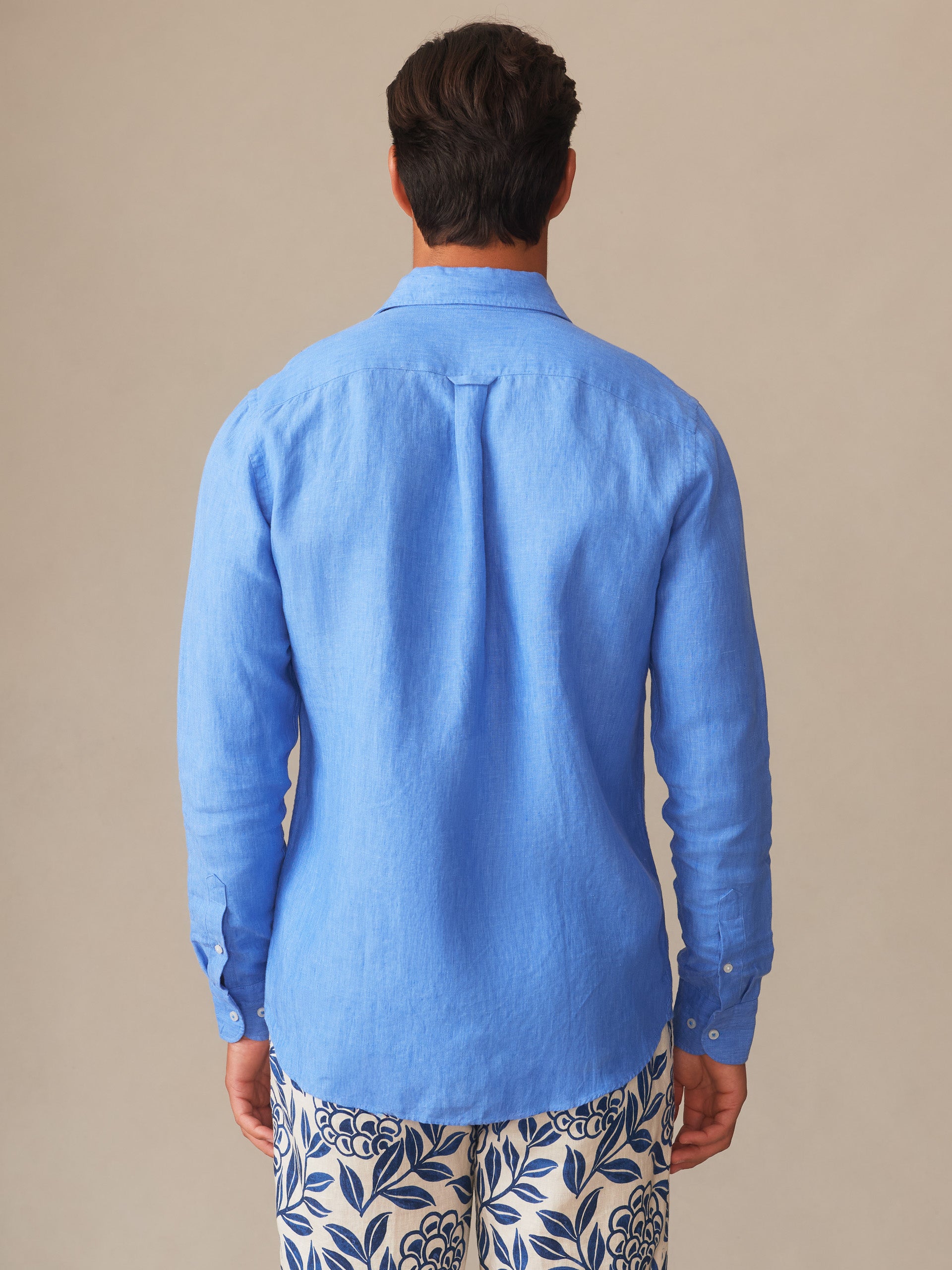 Man wearing a French blue Gramercy Linen Shirt by J.McLaughlin, showcasing effortlessly stylish fit and enduring design, perfect for a destination for defining style. Life, Well-Lived.