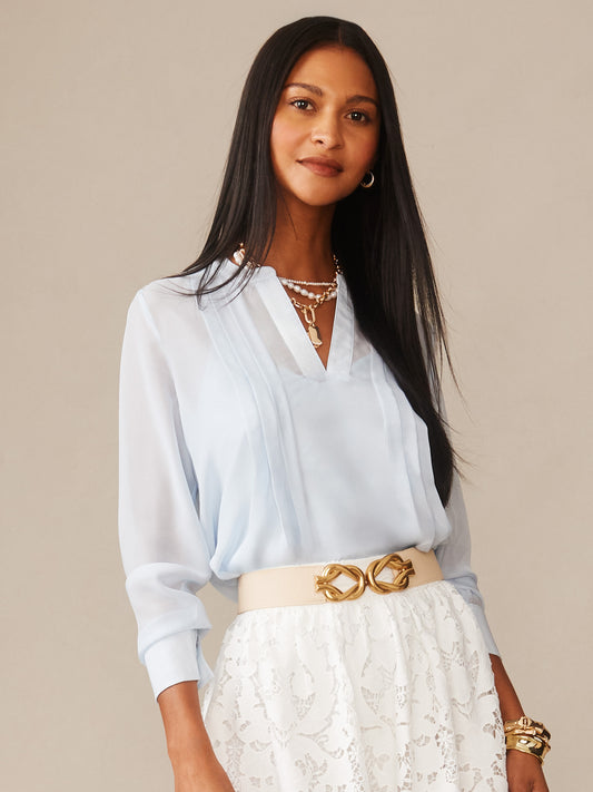 Woman wearing a light blue Katherine Silk Chiffon Blouse by J.McLaughlin paired with a white lace skirt and gold accessories, showcasing effortlessly stylish, enduring designs and innovative fabrics.