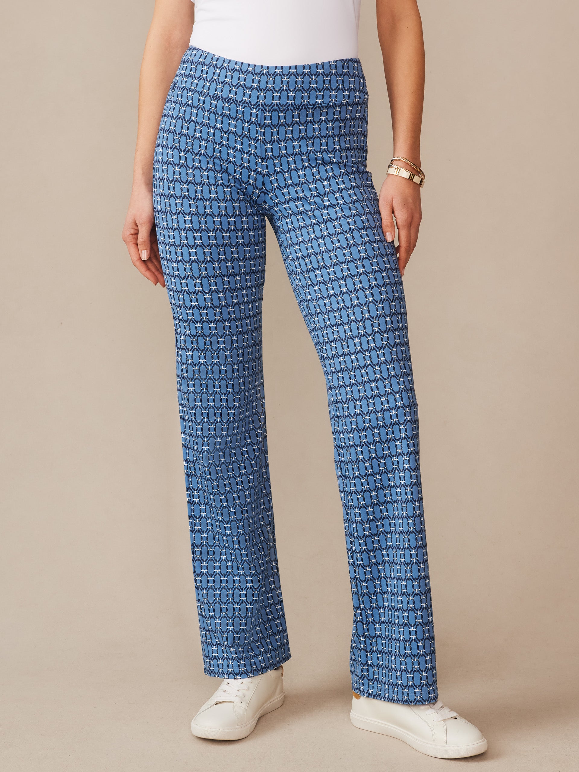 Woman wearing J.McLaughlin Carmel Pants in Signet Lock blue patterned fabric paired with white sneakers, showcasing effortlessly stylish, enduring designs with innovative fabrics.