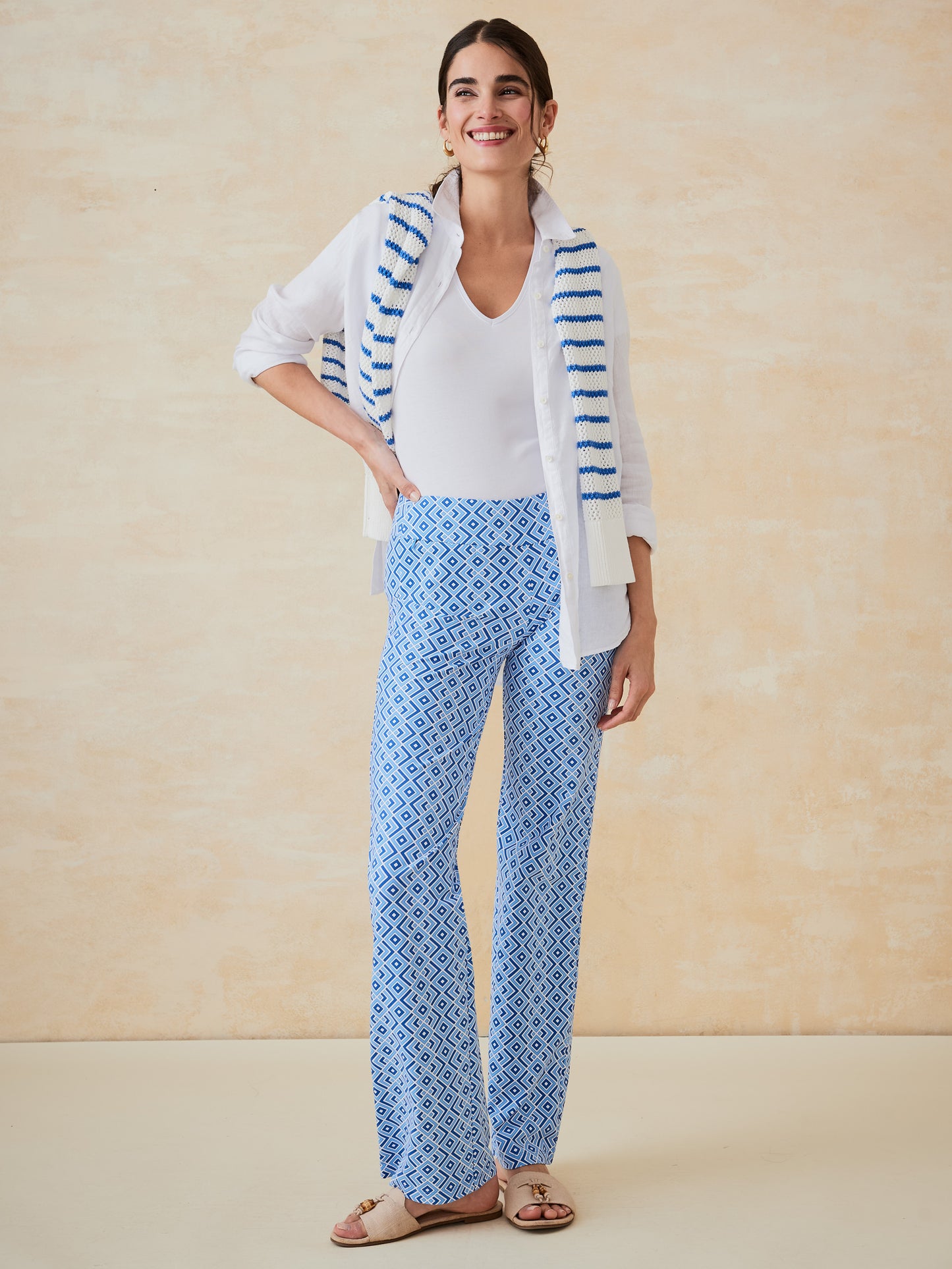 Woman wearing Carmel Pants in Quilted Diamond by J.McLaughlin, styled with a white top, a striped sweater draped over her shoulders, and sandals, showcasing effortlessly stylish, enduring designs and innovative fabrics. A destination for defining style. Life, Well-Lived.