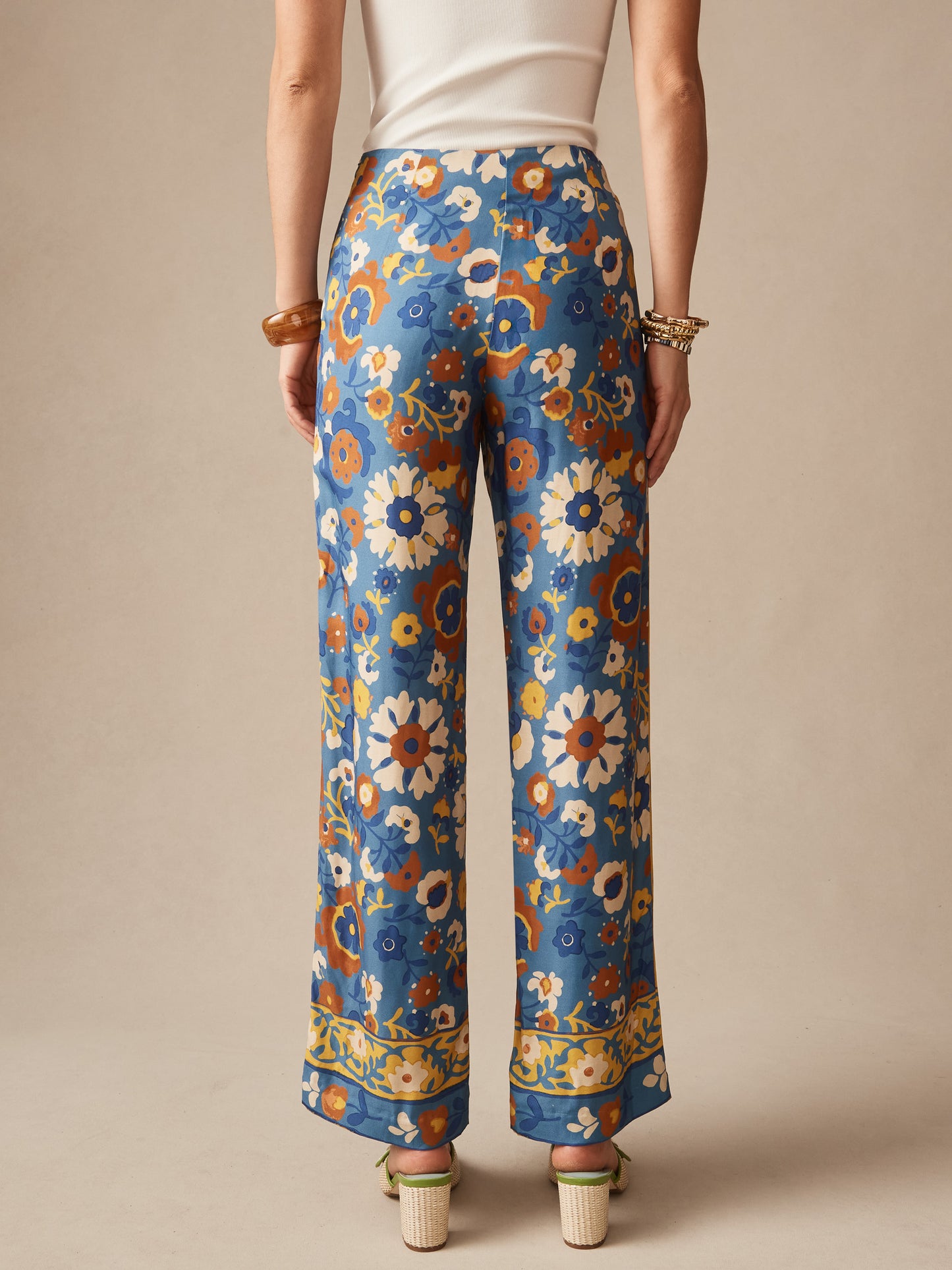 Back view of a woman wearing Carter Silk Blend Pants in Floral Daydream Edge by J.McLaughlin, featuring intricate blue and earth-toned floral patterns, embodying effortlessly stylish, enduring designs with innovative fabrics and a legacy of timeless fashion; a destination for defining style. Life, Well-Lived.