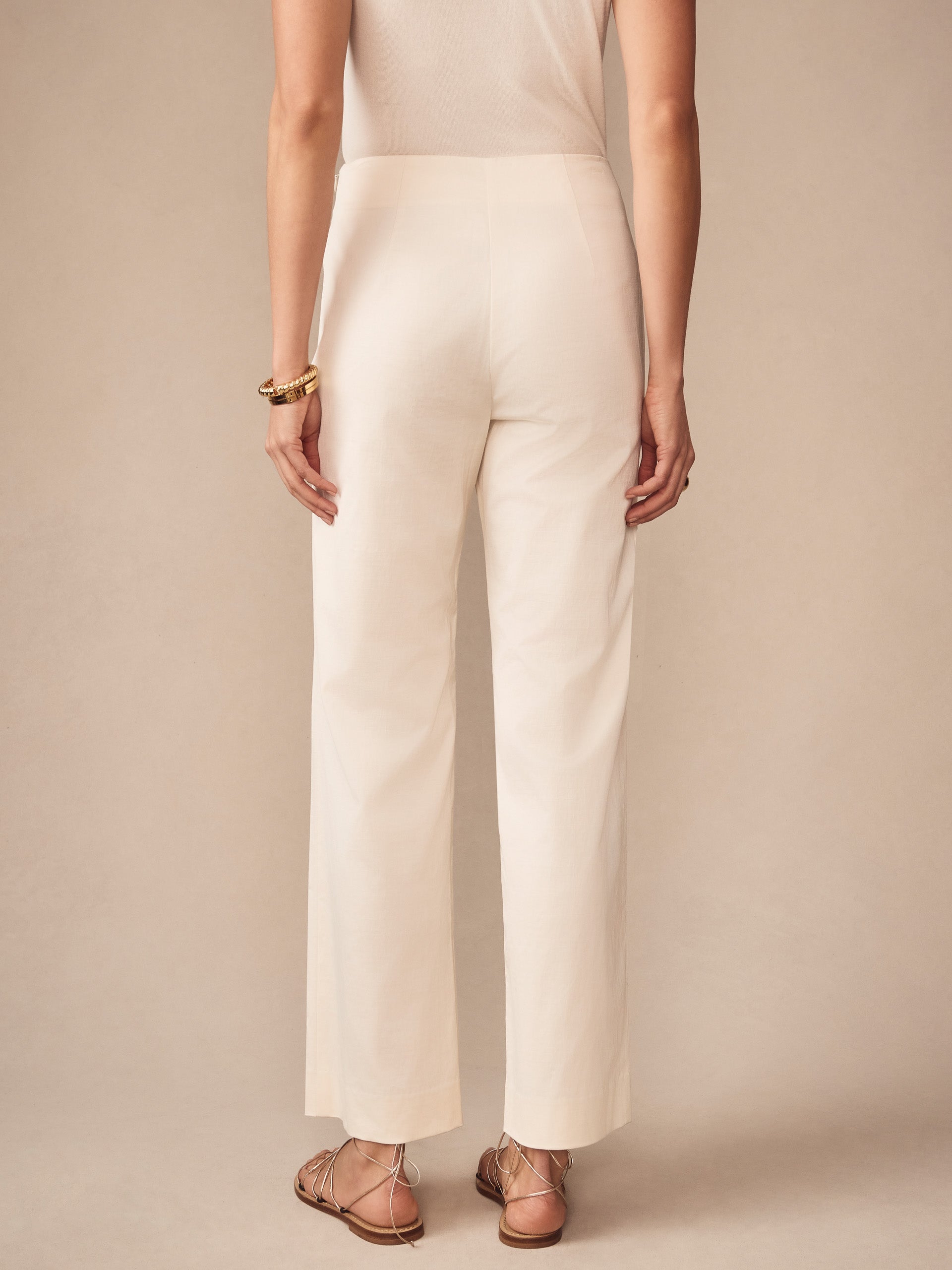 Back view of a woman wearing cream Carter Dupioni Cotton Pants by J.McLaughlin, paired with tan sandals and gold bangles, showcasing effortlessly stylish, enduring designs in innovative fabrics.