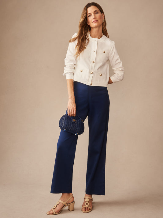 Woman wearing J.McLaughlin Carter Dupioni Cotton Pants in navy, paired with a white buttoned jacket, holding a small navy handbag, embodying effortlessly stylish and enduring designs.