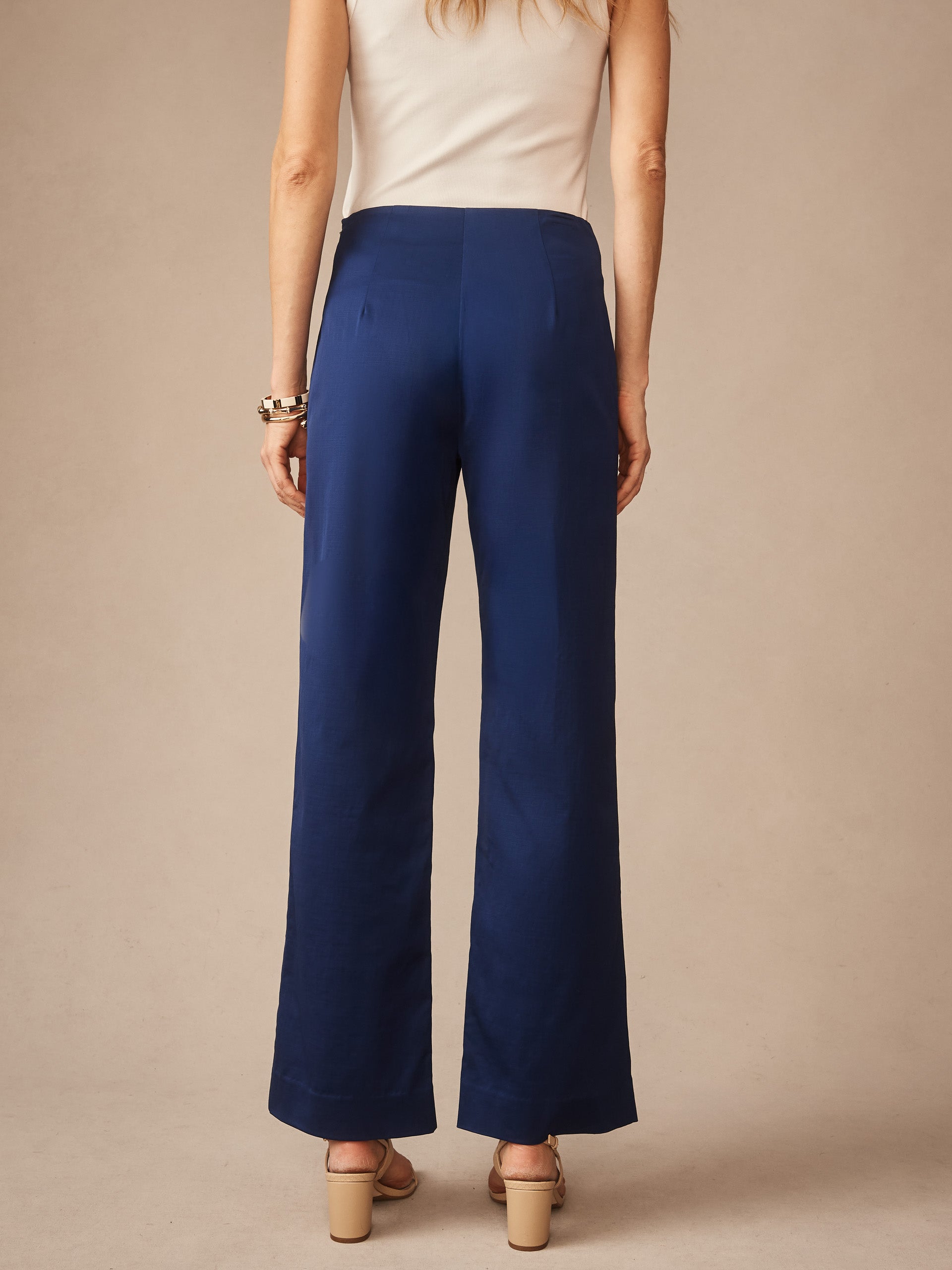 Woman wearing J.McLaughlin Carter Dupioni Cotton Pants in navy blue, styled with a sleeveless top and sandals, showcasing effortlessly stylish fit and enduring designs.