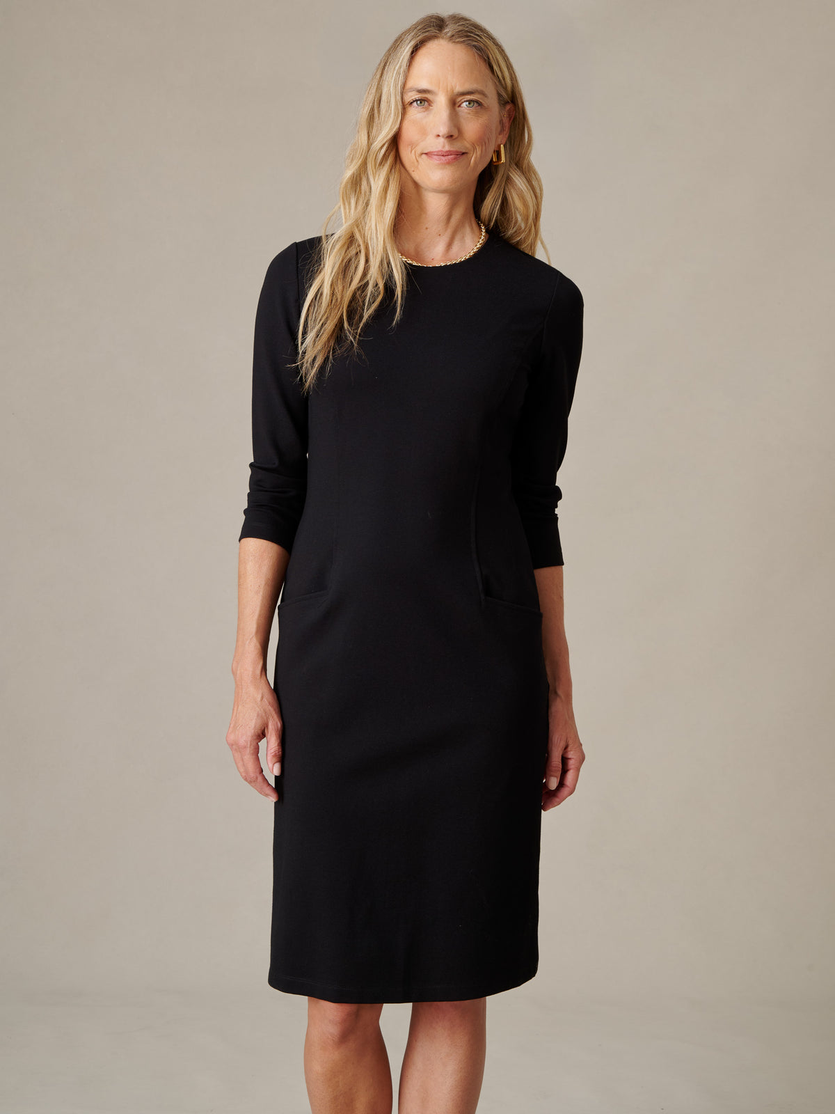 J.McLaughlin Catalyst Dress in black with a tailored silhouette and long sleeves modeled against a neutral studio backdrop