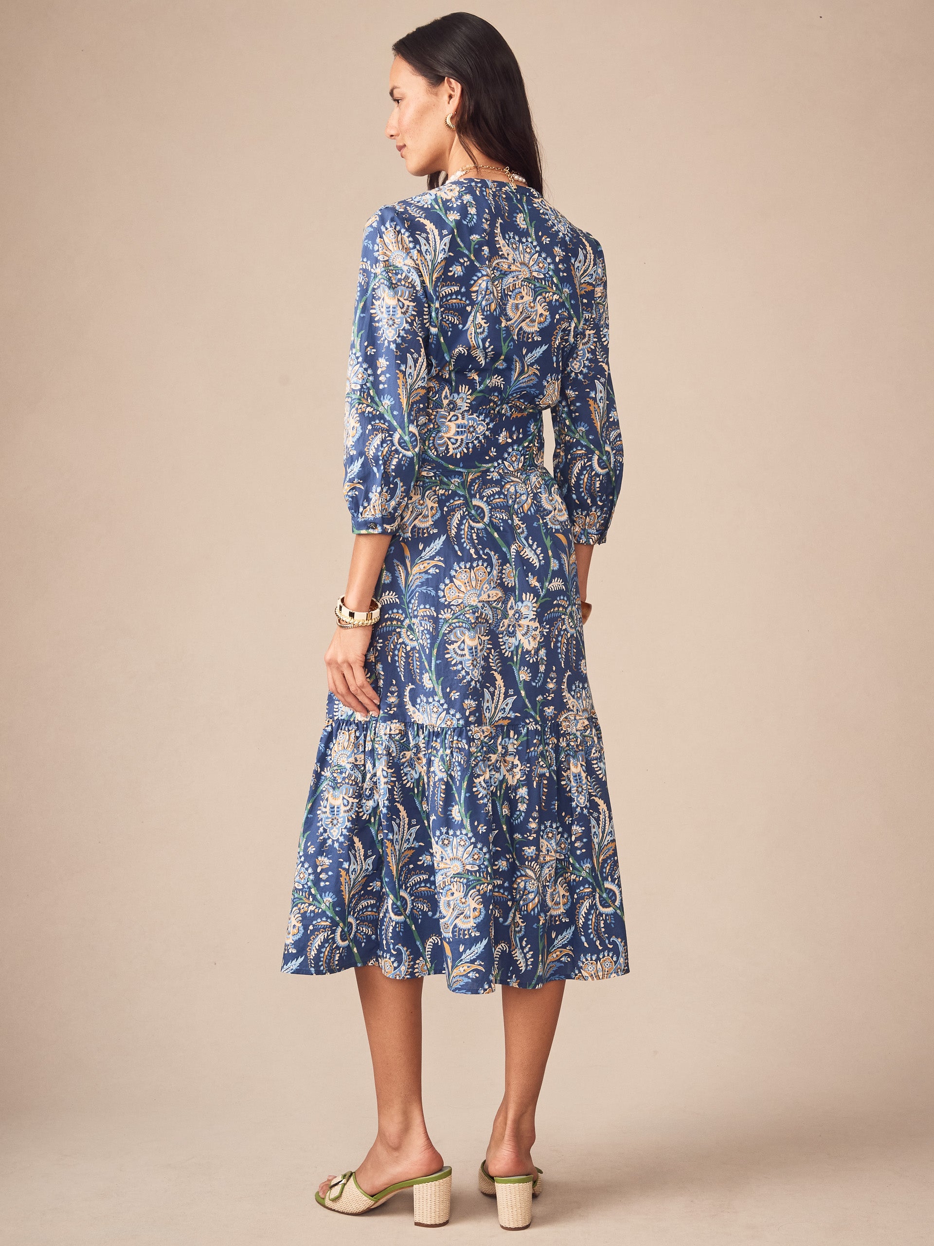A woman wearing the Cerina Dress in Maxi Heirloom Paisley by J.McLaughlin, featuring an elegant blue paisley pattern with three-quarter sleeves, embodying effortlessly stylish, enduring designs and a legacy of timeless fashion. A destination for defining style. Life, Well-Lived.