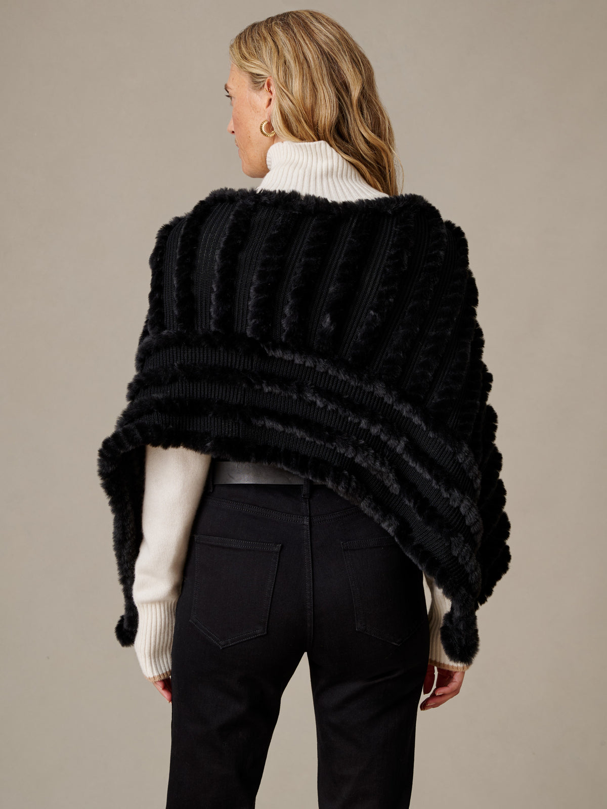 J.McLaughlin Charlie Faux Fur Poncho in black faux fur styled over a white turtleneck with black pants for timeless winter elegance