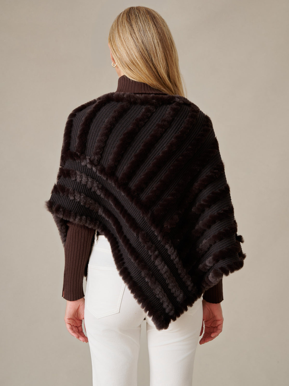 J.McLaughlin Charlie Faux Fur Poncho in dark brown faux fur shown from the back with a ribbed sweater and white pants for timeless winter style