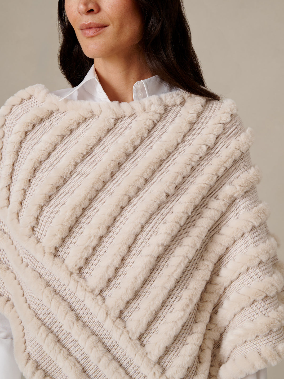 J.McLaughlin Charlie Faux Fur Poncho in cream faux fur with textured stripes layered over a white shirt for timeless winter style