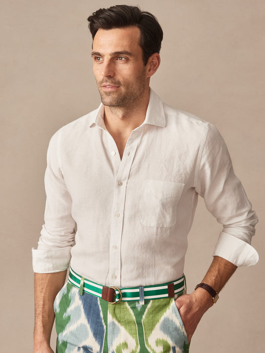 Man wearing a white Gramercy Linen Shirt by J.McLaughlin paired with green and blue patterned pants, showcasing effortlessly stylish, enduring designs and innovative fabrics.