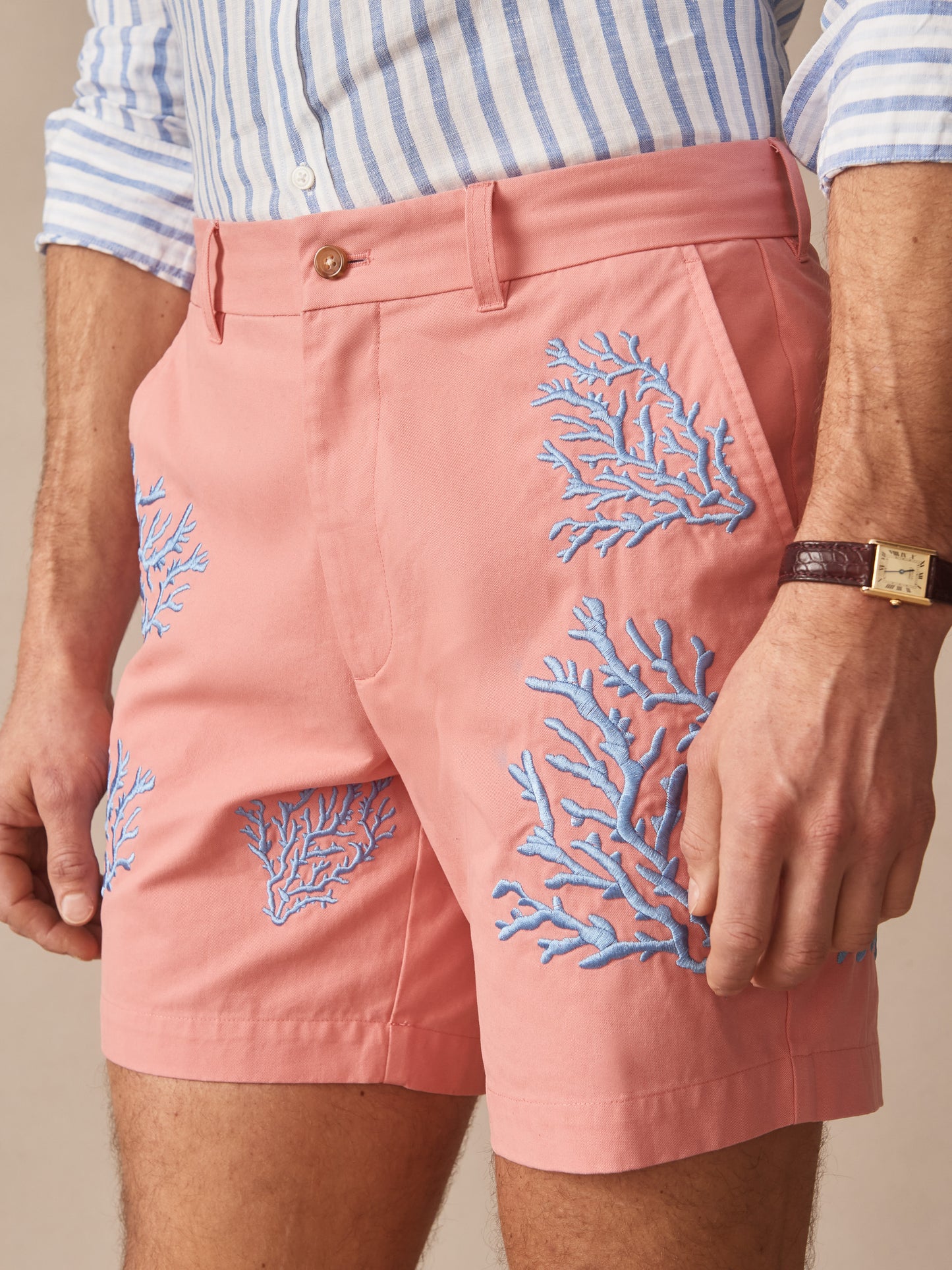 Close-up of a man wearing Chatham Embroidered Shorts in Coral by J.McLaughlin, featuring effortlessly stylish design with blue embroidery on coral fabric, embodying enduring designs and a legacy of timeless fashion. A destination for defining style. Life, Well-Lived.