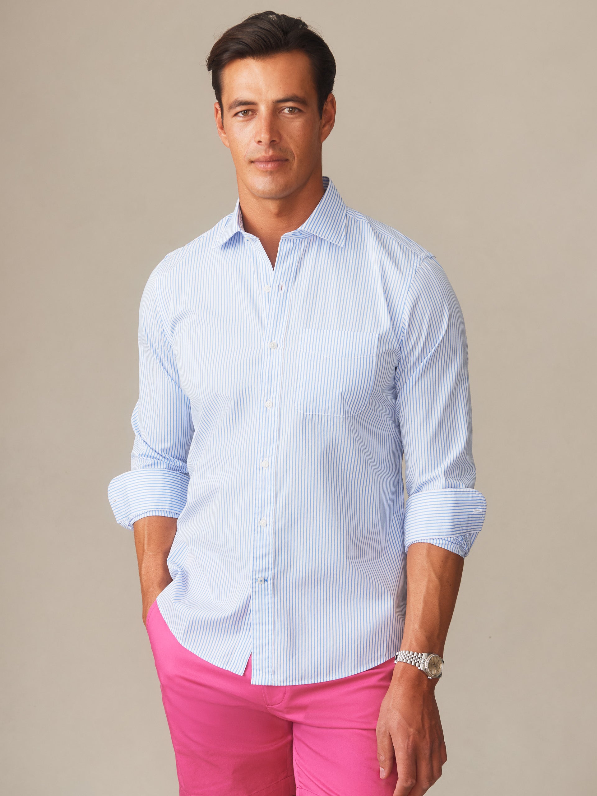Man wearing a Gramercy Cotton Shirt in Pencil Stripe by J.McLaughlin paired with bright pink shorts, showcasing effortlessly stylish, enduring designs and innovative fabrics.
