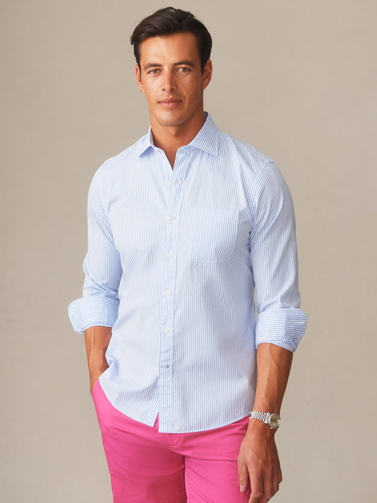 Man wearing a Gramercy Cotton Shirt in Pencil Stripe by J.McLaughlin paired with bright pink shorts, showcasing effortlessly stylish, enduring designs and innovative fabrics.