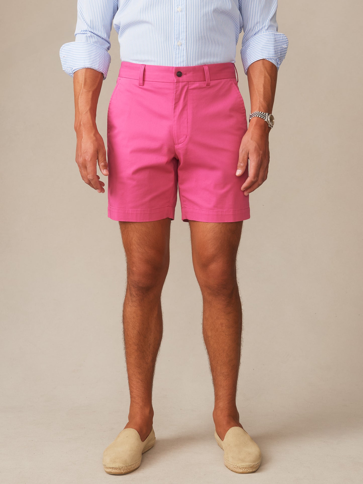 Man wearing hot pink Chatham Shorts by J.McLaughlin paired with a light blue striped shirt and beige slip-on shoes, showcasing effortlessly stylish, enduring designs and innovative fabrics.