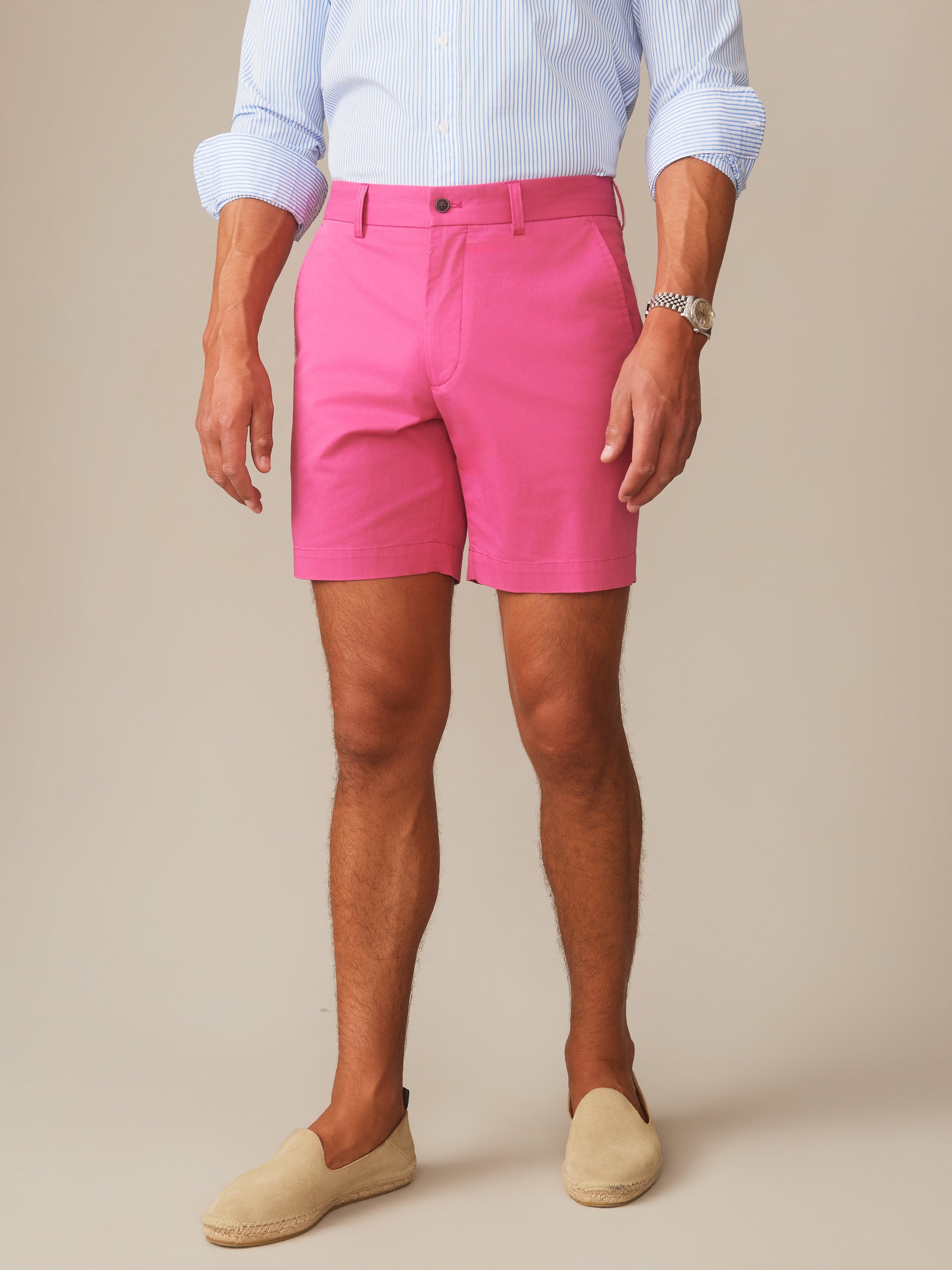 Man wearing hot pink Chatham Shorts by J.McLaughlin paired with a light blue striped shirt and beige espadrilles, showcasing effortlessly stylish, enduring designs for a life well-lived.