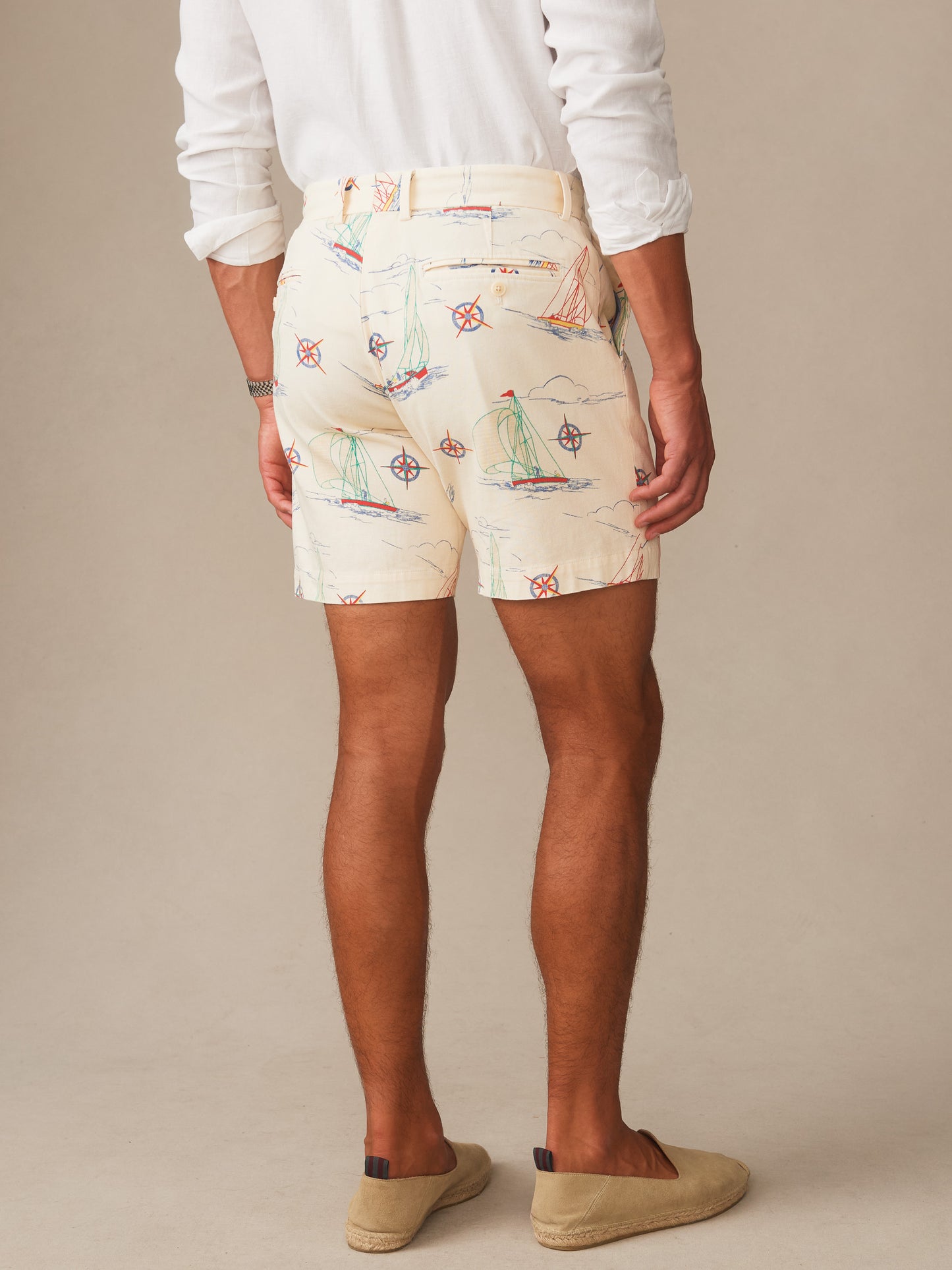 Man wearing Chatham Shorts in Compass Points by J.McLaughlin featuring nautical compass and sailboat motifs on cream fabric, pairing effortlessly stylish design with enduring appeal. A destination for defining style. Life, Well-Lived.