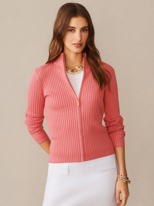 Woman wearing a pink Clemence Zip Cardigan by J.McLaughlin, styled with a white top and skirt, showcasing effortlessly stylish, enduring designs in innovative fabrics for a legacy of timeless fashion.
