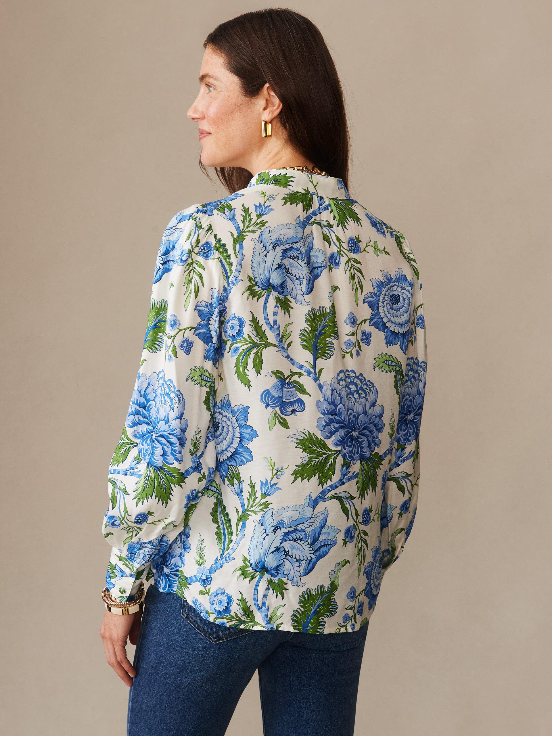 Woman wearing a Maeve Silk Blend Blouse in Cerulean Garden by J.McLaughlin, featuring an effortlessly stylish floral pattern in blue and green on an off-white background, exemplifying enduring designs and innovative fabrics for a life well-lived.