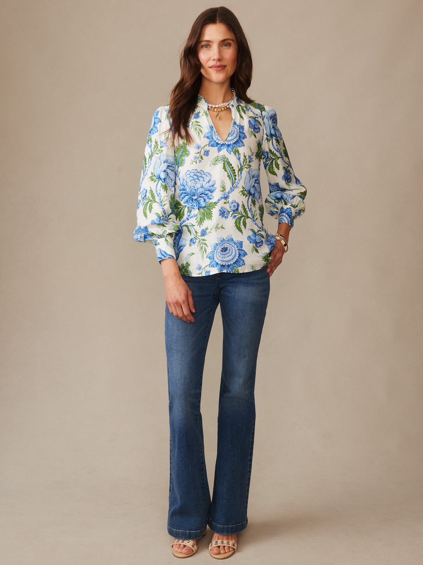 Woman wearing a Maeve Silk Blend Blouse in Cerulean Garden by J.McLaughlin, styled with blue floral patterns, paired with jeans and sandals, showcasing effortlessly stylish and enduring designs.