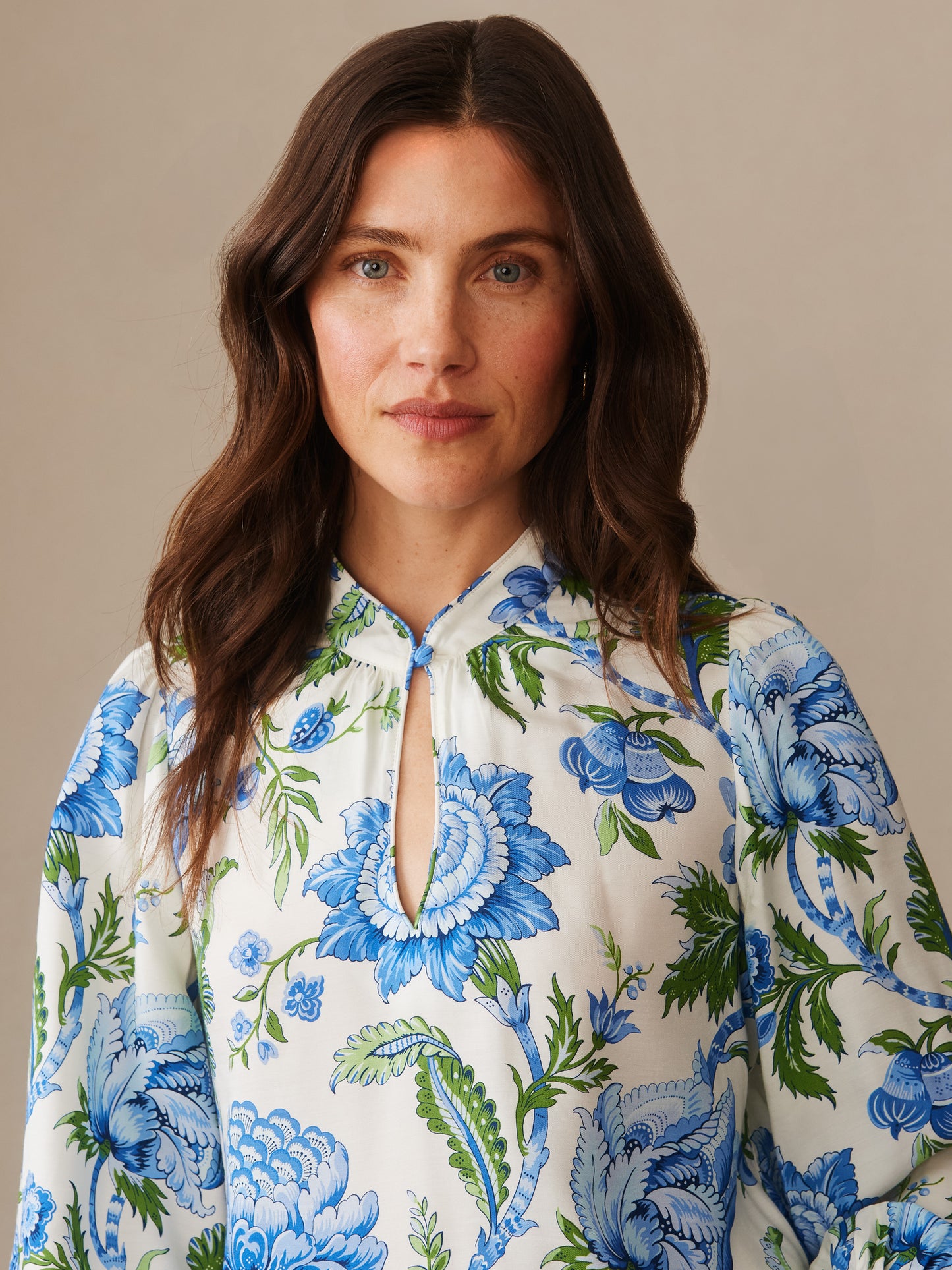 Close-up portrait of a woman wearing a Maeve Silk Blend Blouse in Cerulean Garden by J.McLaughlin, featuring blue and green floral patterns on a white background, exemplifying effortlessly stylish, enduring designs with innovative fabrics from a legacy of timeless fashion at a destination for defining style. Life, Well-Lived.