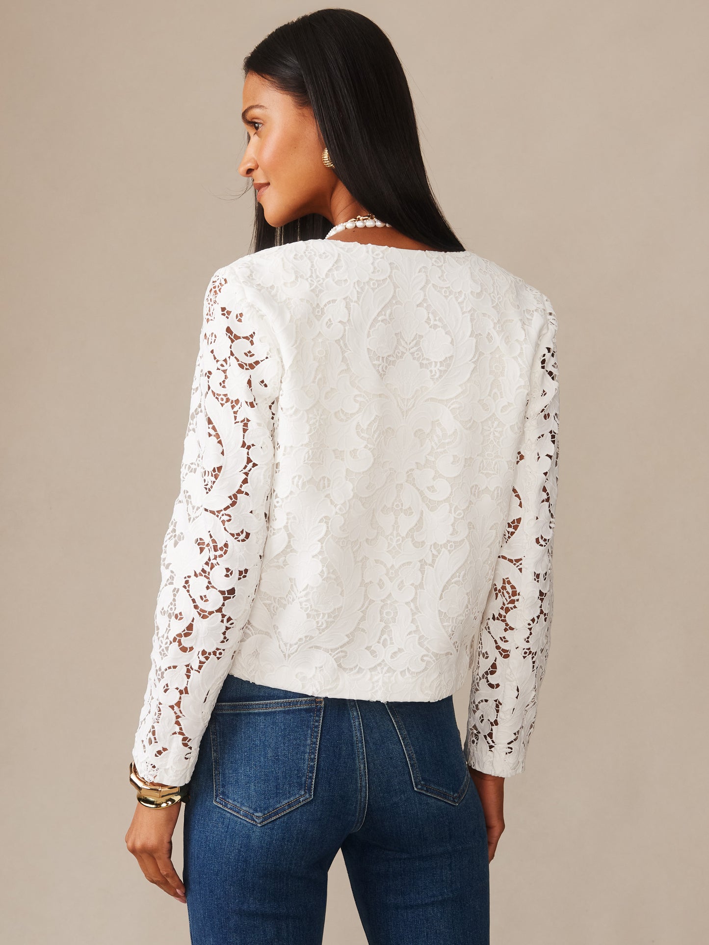 A woman wearing an off-white Coco Lace Jacket by J.McLaughlin, showcasing intricate lace sleeves and a classic, timeless design that reflects effortlessly stylish, enduring designs with a legacy of timeless fashion.