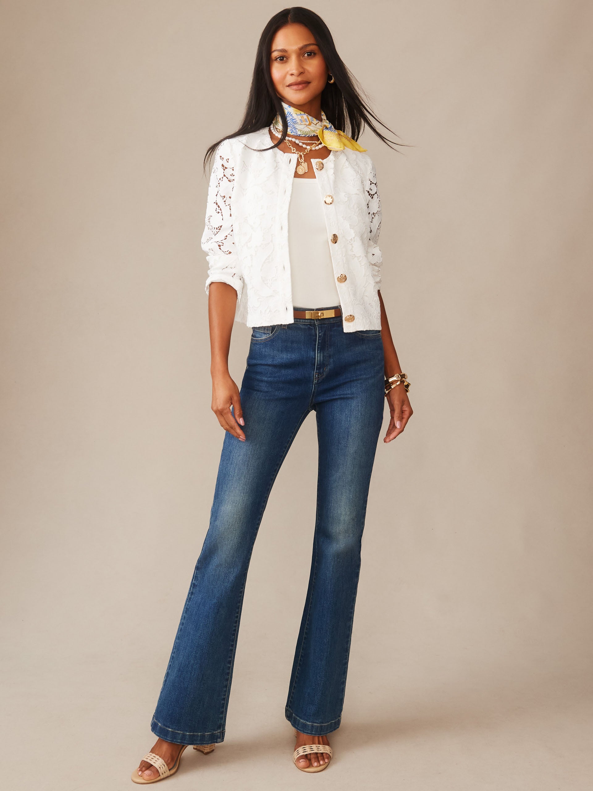Woman wearing a white Coco Lace Jacket by J.McLaughlin over a white top with dark blue jeans, accessorized with a yellow and blue scarf and sandals, showcasing effortlessly stylish and enduring designs from a destination for defining style. Life, Well-Lived.