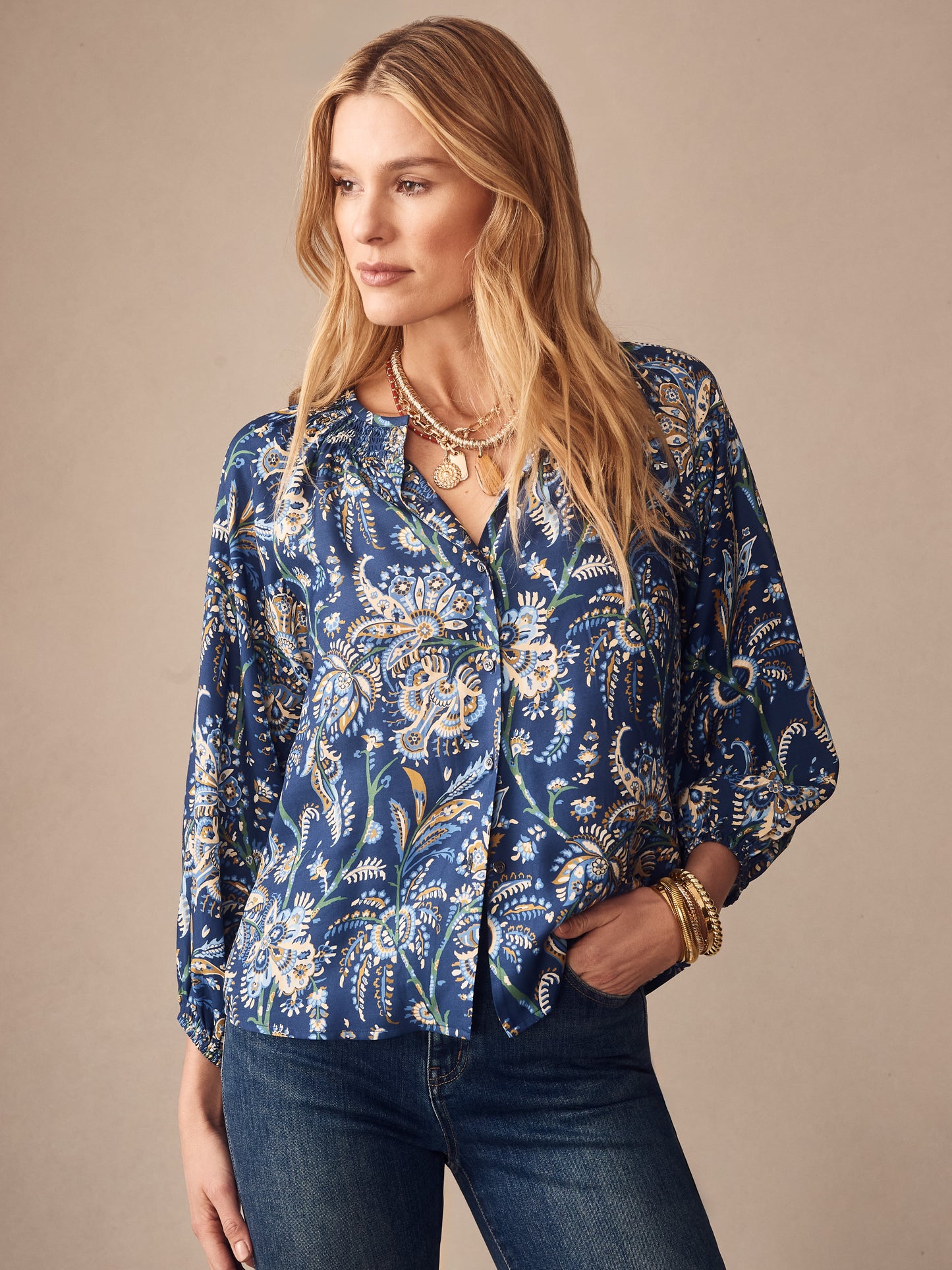 Woman wearing J.McLaughlin Constance Silk Blend Blouse in Maxi Heirloom Paisley with blue and white floral pattern, styled with jeans and gold accessories, showcasing effortlessly stylish, enduring designs and innovative fabrics for a life well-lived.