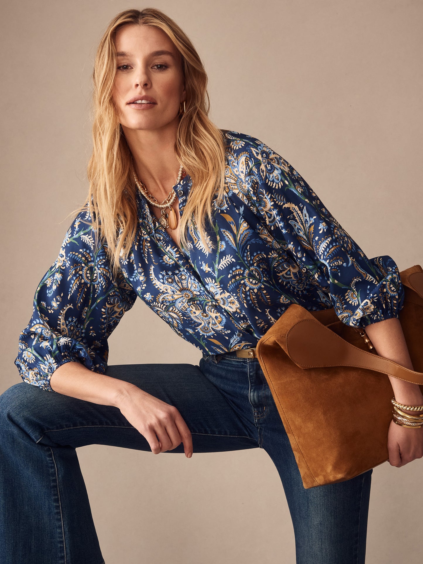 Woman wearing a Constance Silk Blend Blouse in Maxi Heirloom Paisley by J.McLaughlin, styled with jeans and a brown suede bag, capturing effortlessly stylish, enduring designs in innovative fabrics.