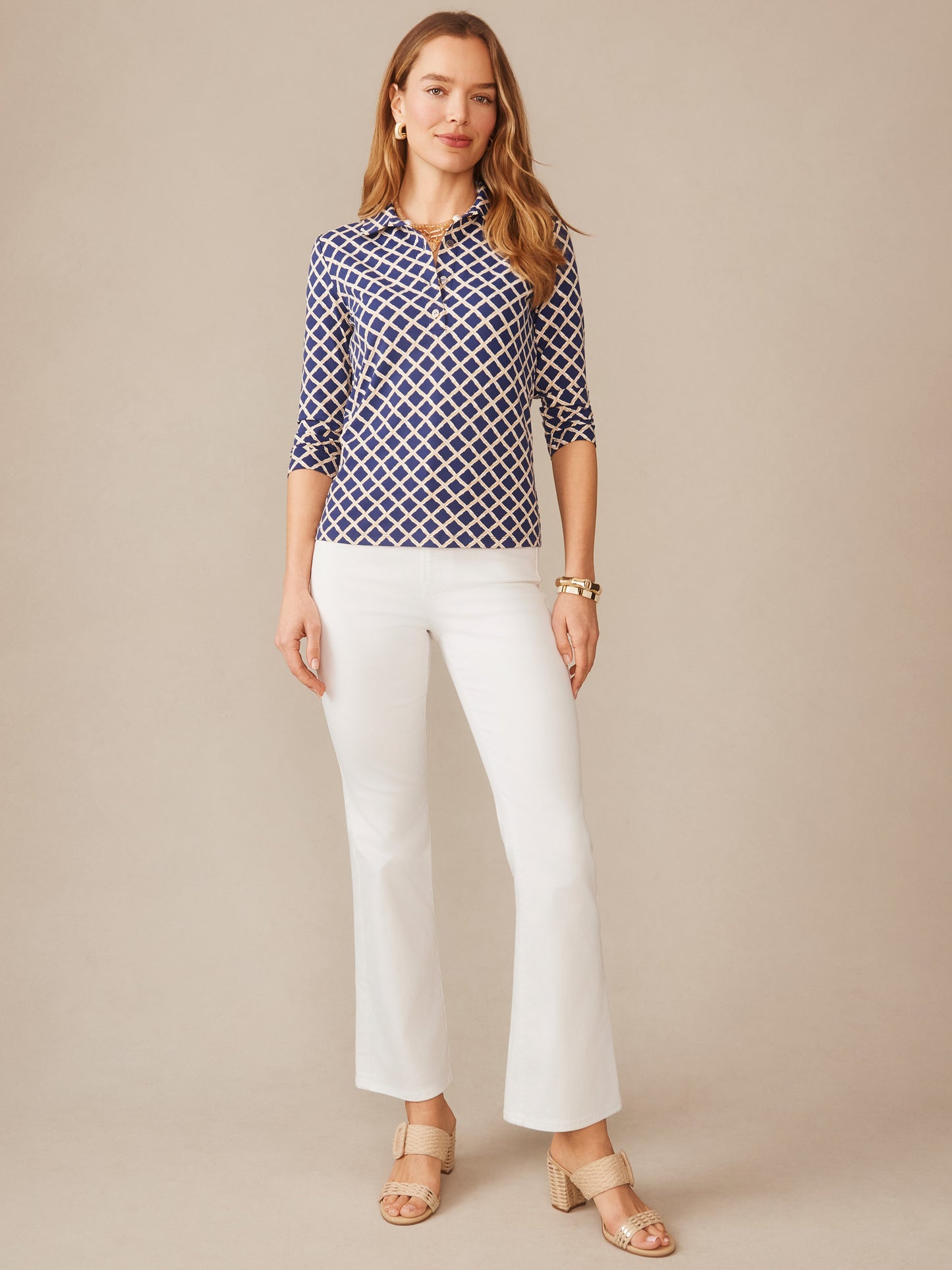 Woman wearing a stylish Court 3/4 Sleeve Polo in Micro Bamboo with a navy and sand geometric pattern, paired with white pants and beige sandals, reflecting J.McLaughlin’s legacy of timeless fashion.