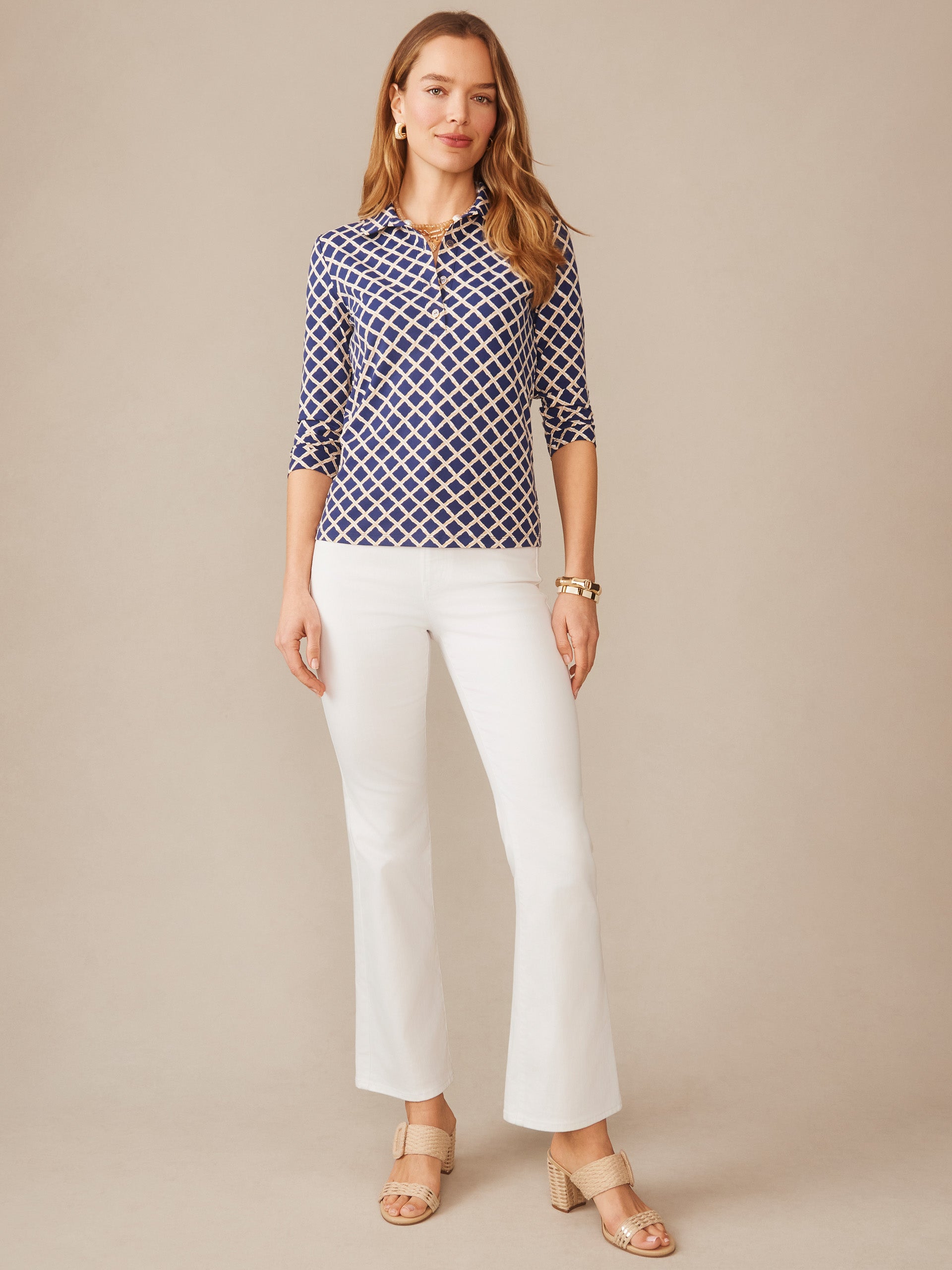 Woman wearing a stylish Court 3/4 Sleeve Polo in Micro Bamboo with a navy and sand geometric pattern, paired with white pants and beige sandals, reflecting J.McLaughlin’s legacy of timeless fashion.