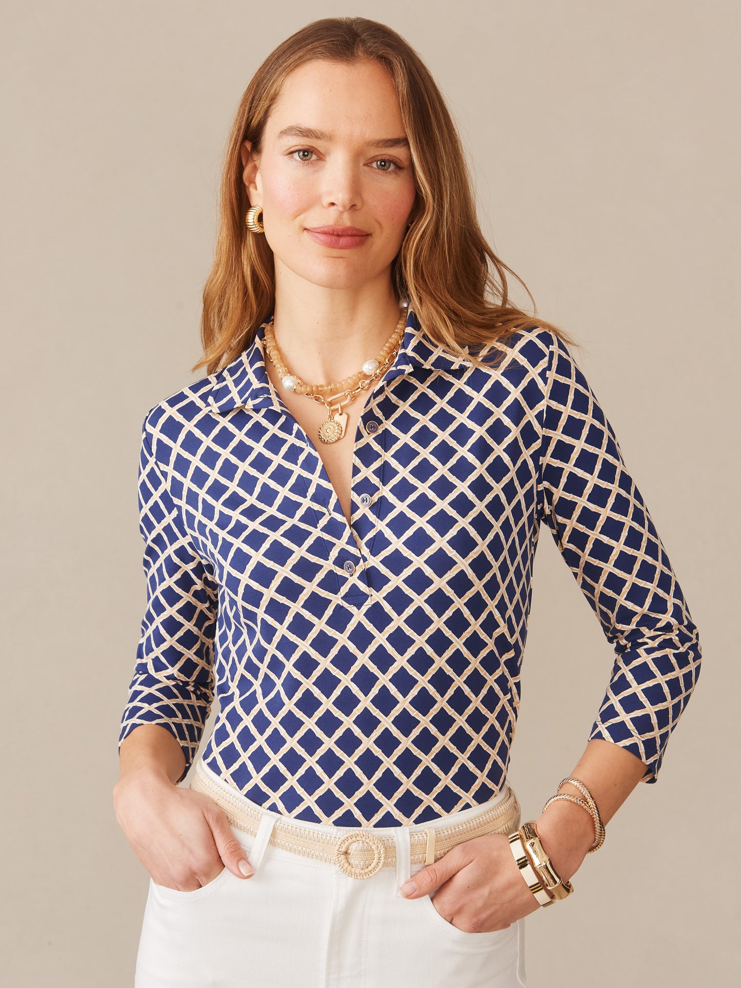 Woman wearing a patterned Court 3/4 Sleeve Polo in Micro Bamboo by J.McLaughlin, styled with white pants and elegant jewelry, showcasing effortlessly stylish, enduring designs and innovative fabrics. A destination for defining style. Life, Well-Lived.