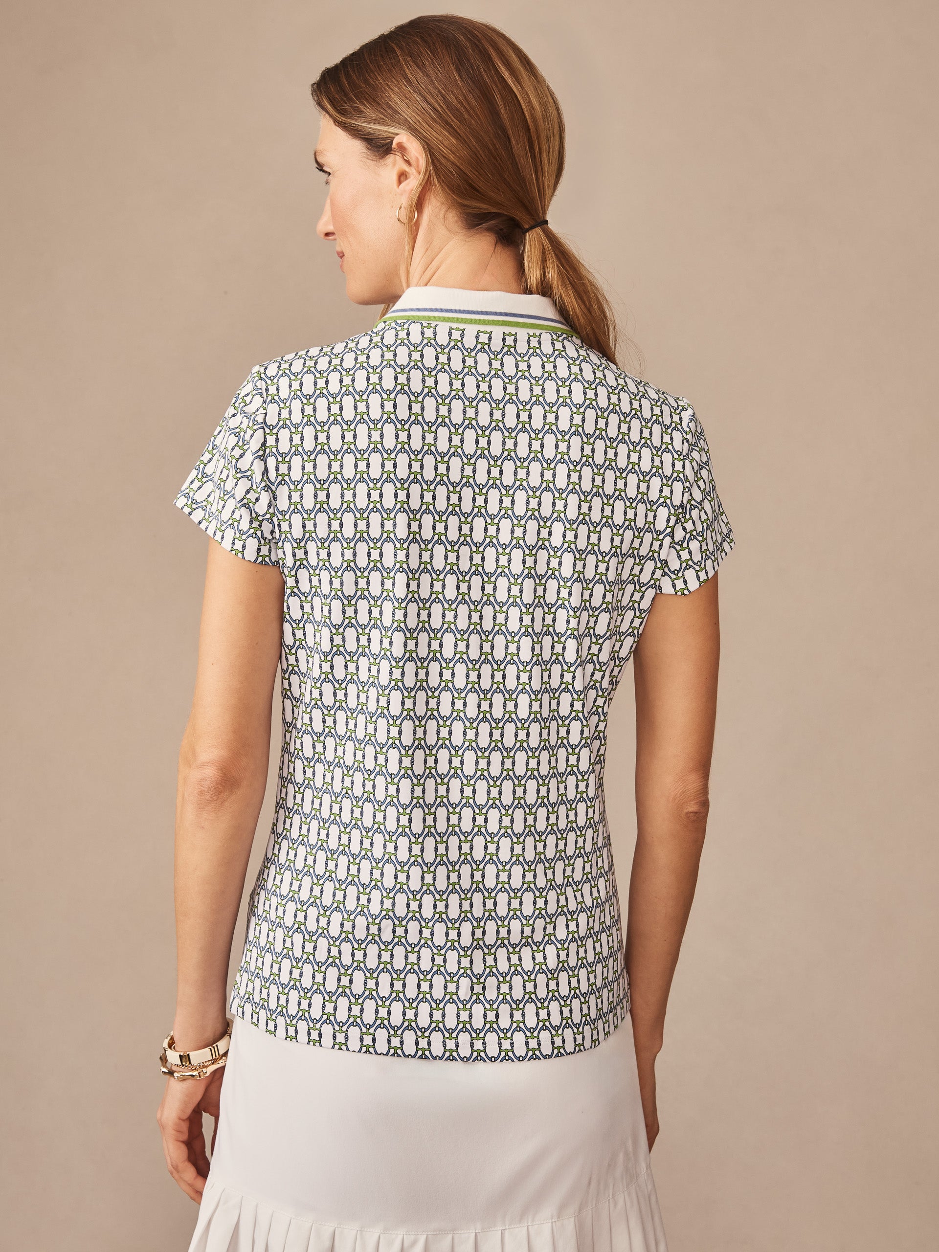 A woman wearing a Court Cap Sleeve Polo in Signet Lock by J.McLaughlin, featuring effortlessly stylish, enduring designs and innovative fabrics that reflect a legacy of timeless fashion.