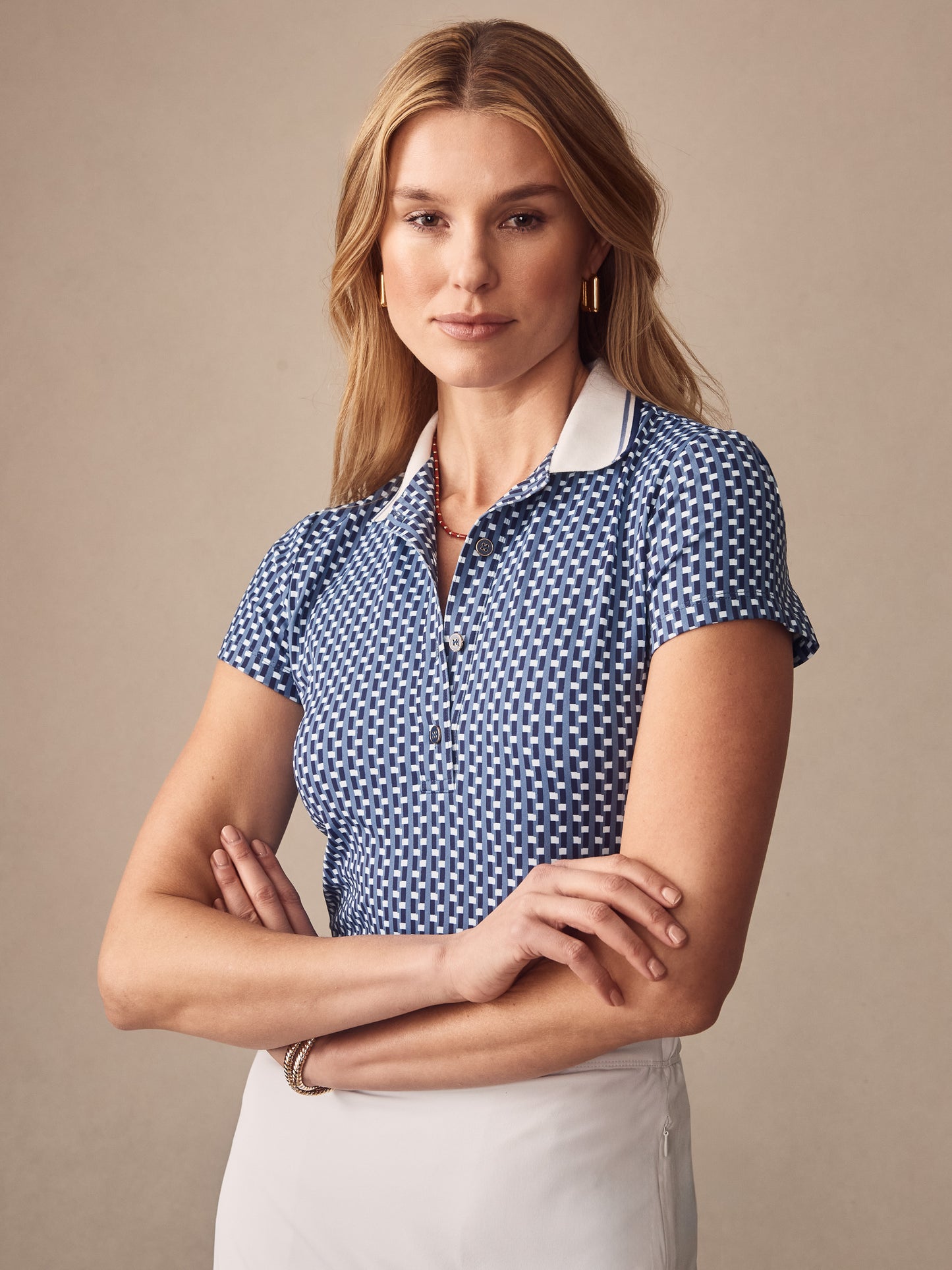 Woman wearing a blue and white patterned Court Cap Sleeve Polo in Azrou by J.McLaughlin, showcasing effortlessly stylish, enduring designs crafted with innovative fabrics for a legacy of timeless fashion. A destination for defining style. Life, Well-Lived.