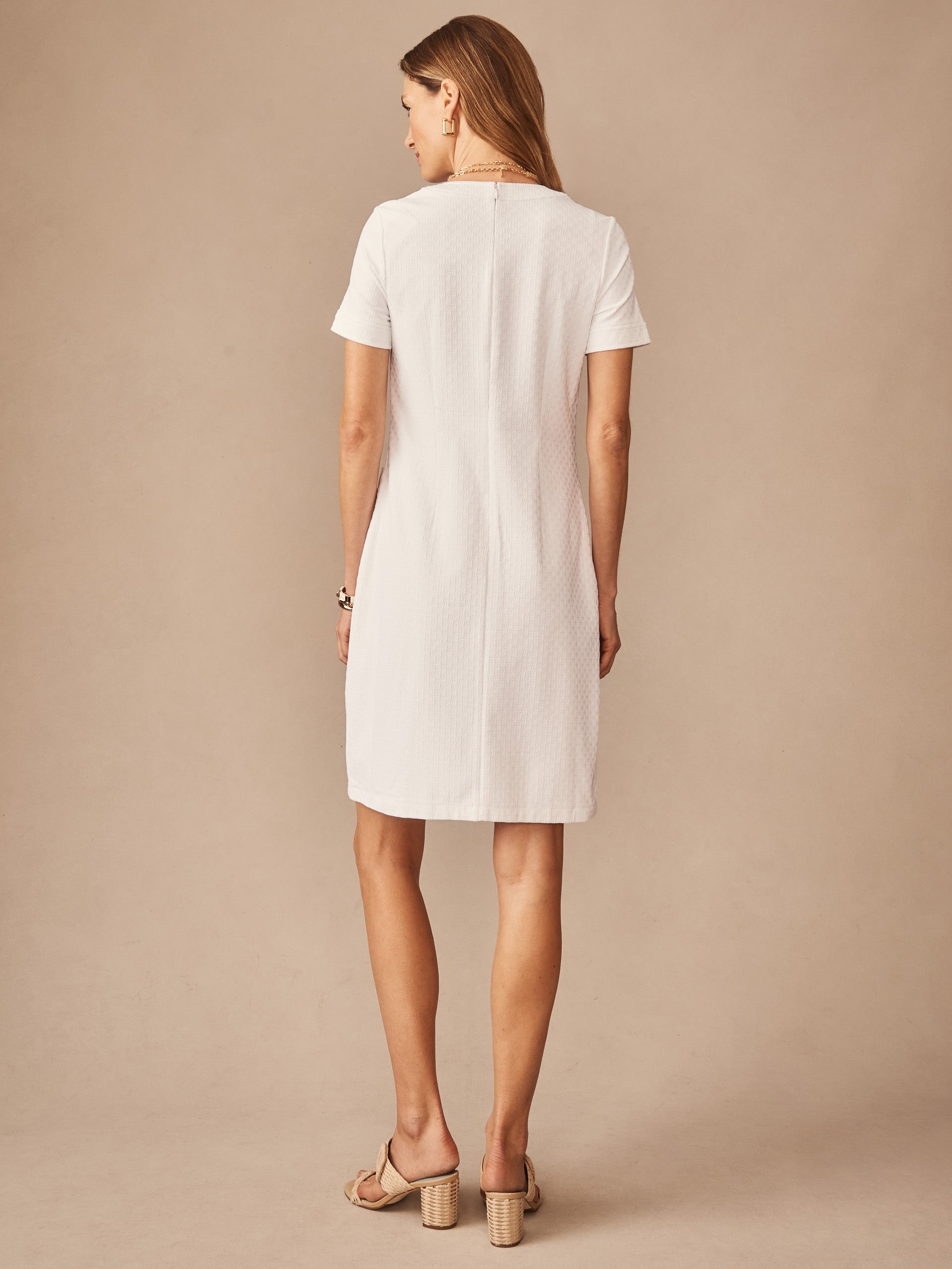 Woman wearing a white Daphne Dress in Dashing Jacquard by J.McLaughlin, showcasing effortlessly stylish, enduring designs with innovative fabrics in a timeless silhouette.