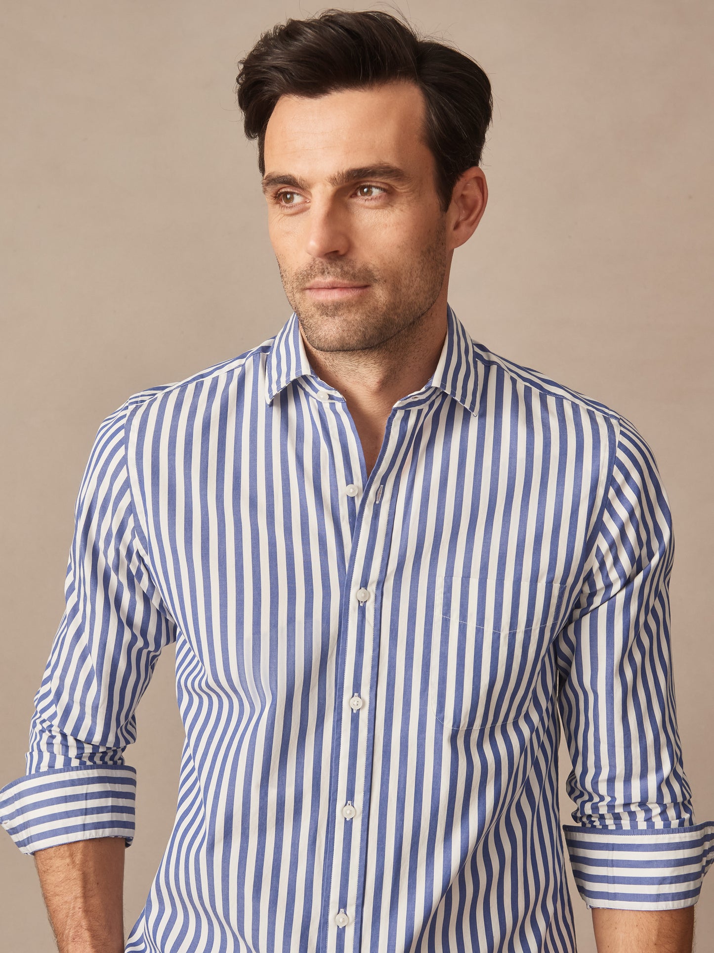 Man wearing a Gramercy Cotton Shirt in Awning Stripe by J.McLaughlin, featuring effortlessly stylish, enduring designs crafted from innovative fabrics in a classic blue and white stripe pattern.