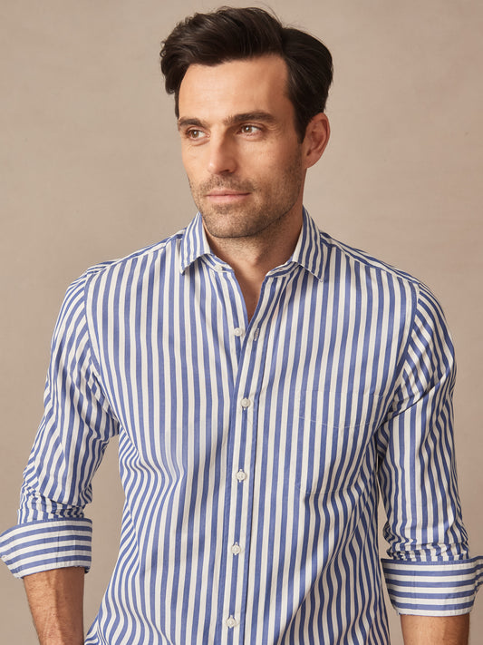 Man wearing a Gramercy Cotton Shirt in Awning Stripe by J.McLaughlin, featuring effortlessly stylish, enduring designs crafted from innovative fabrics in a classic blue and white stripe pattern.