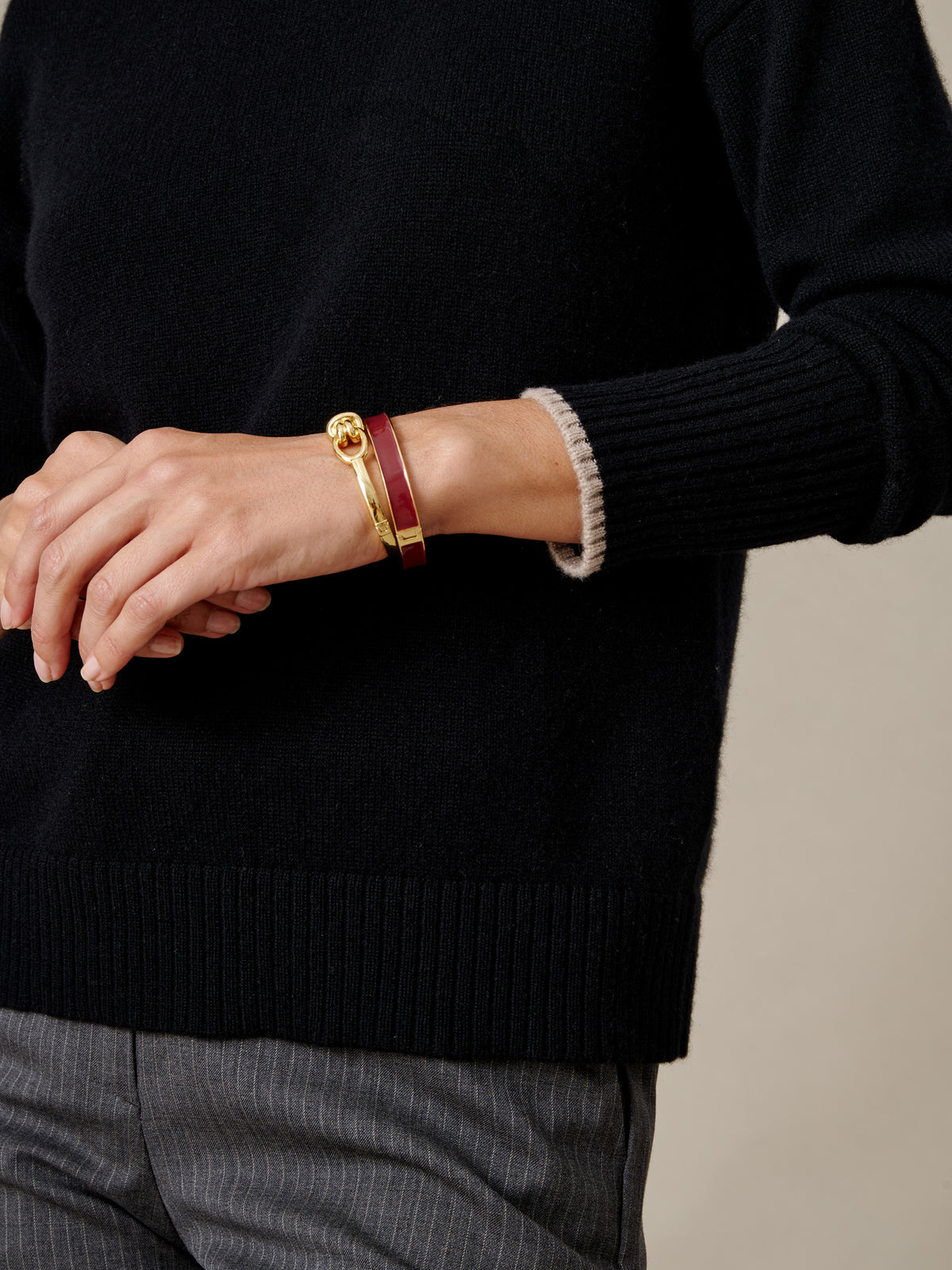 J.McLaughlin Dina Cashmere Turtleneck in black with ribbed cuffs and hem styled with gray trousers and a gold bracelet