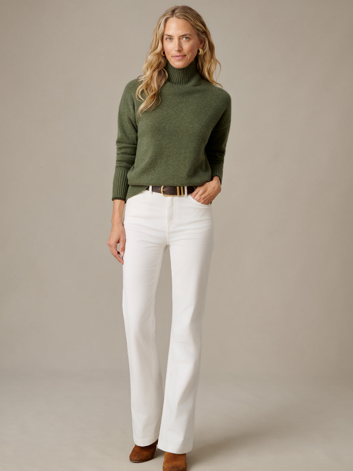 J.McLaughlin Dina Cashmere Turtleneck in olive green styled with white pants and a brown belt on a model