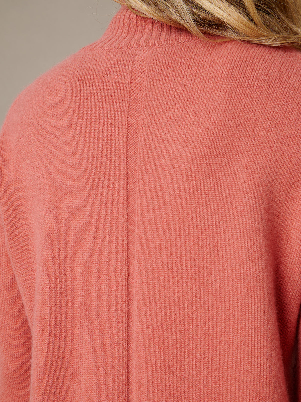 Dina Cashmere Turtleneck in coral cashmere with a soft ribbed collar and clean back seam shown on a model by J.McLaughlin
