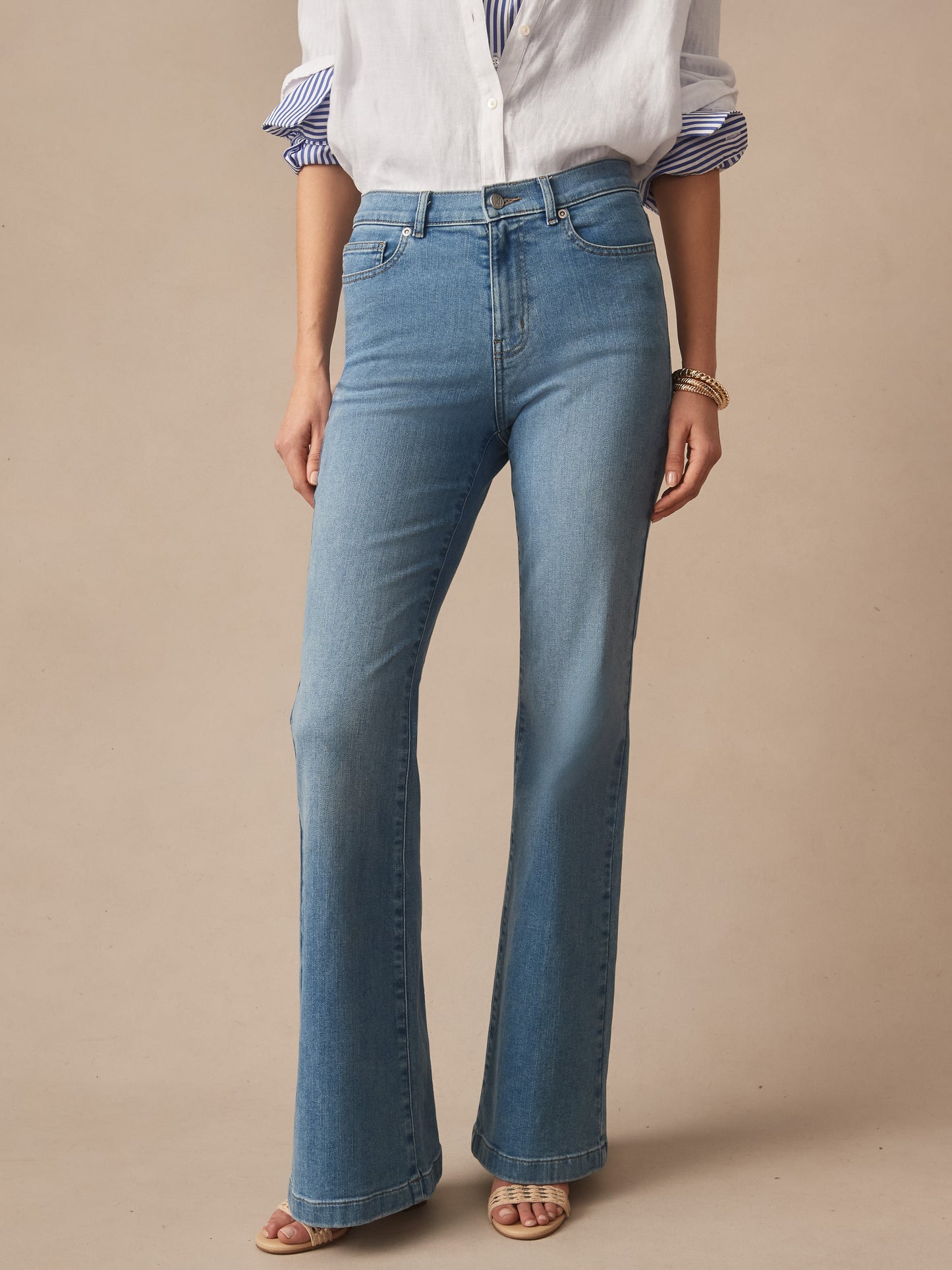 Woman wearing Domino Jeans by J.McLaughlin, featuring an effortlessly stylish, classic blue denim with a flattering high waist and subtle flare, embodying enduring designs and a legacy of timeless fashion. A destination for defining style. Life, Well-Lived.