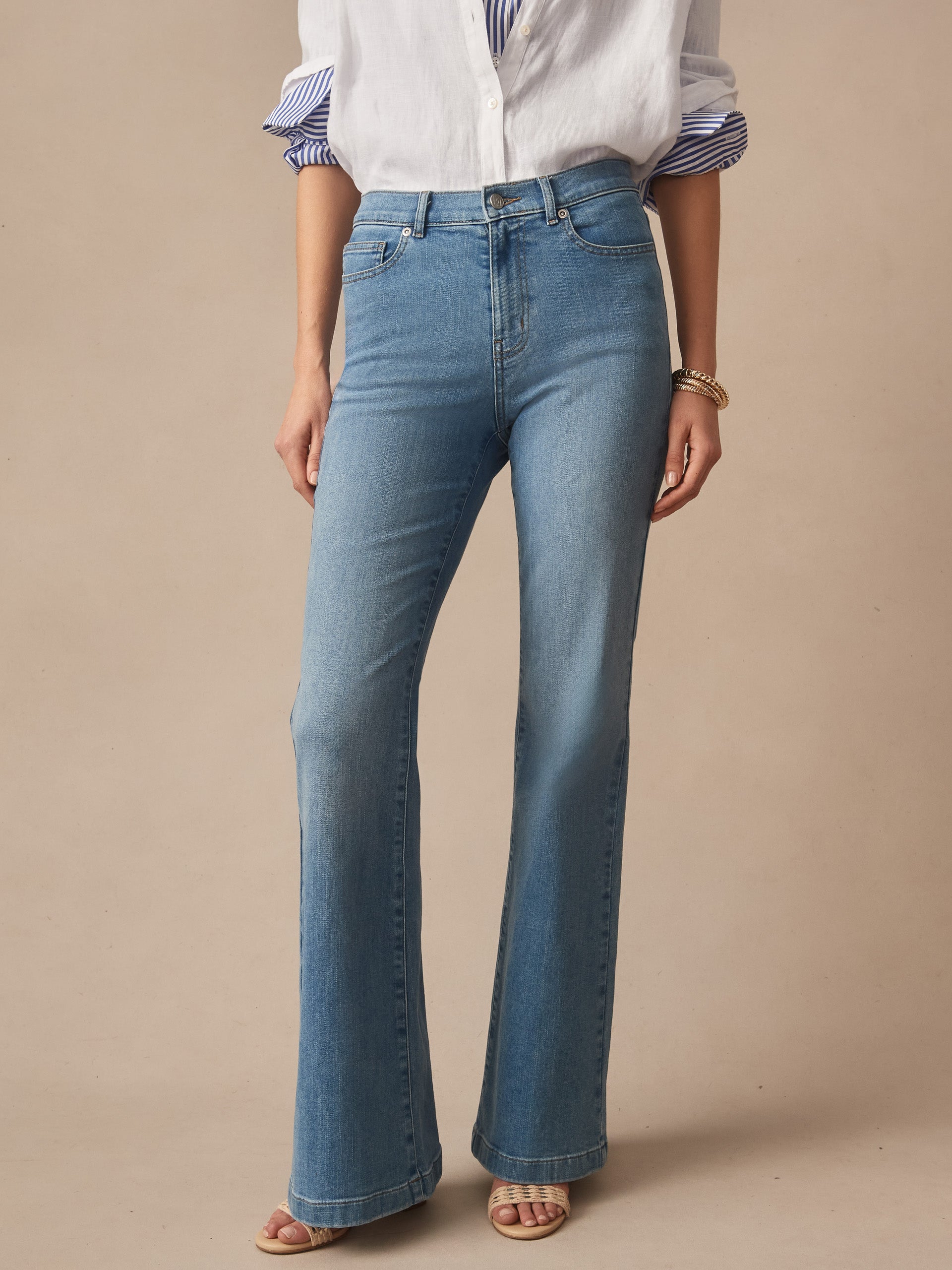Woman wearing Domino Jeans by J.McLaughlin, featuring an effortlessly stylish, classic blue denim with a flattering high waist and subtle flare, embodying enduring designs and a legacy of timeless fashion. A destination for defining style. Life, Well-Lived.