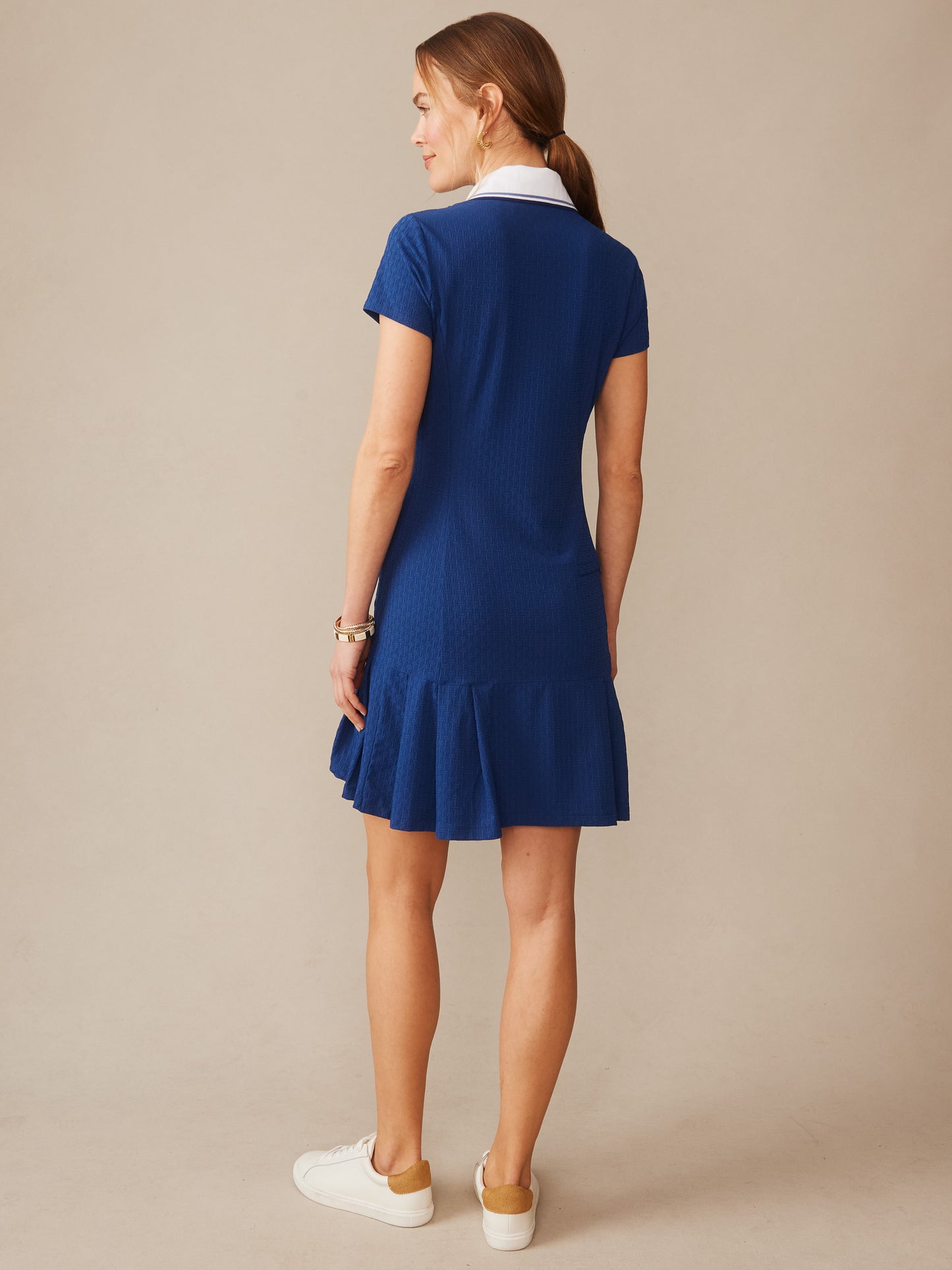 Woman wearing a navy blue short-sleeve dress with a white collar and flared hem by J.McLaughlin, showcasing the Dorte Dress in Dashing Jacquard, embodying effortlessly stylish, enduring designs with innovative fabrics in a legacy of timeless fashion. A destination for defining style. Life, Well-Lived.