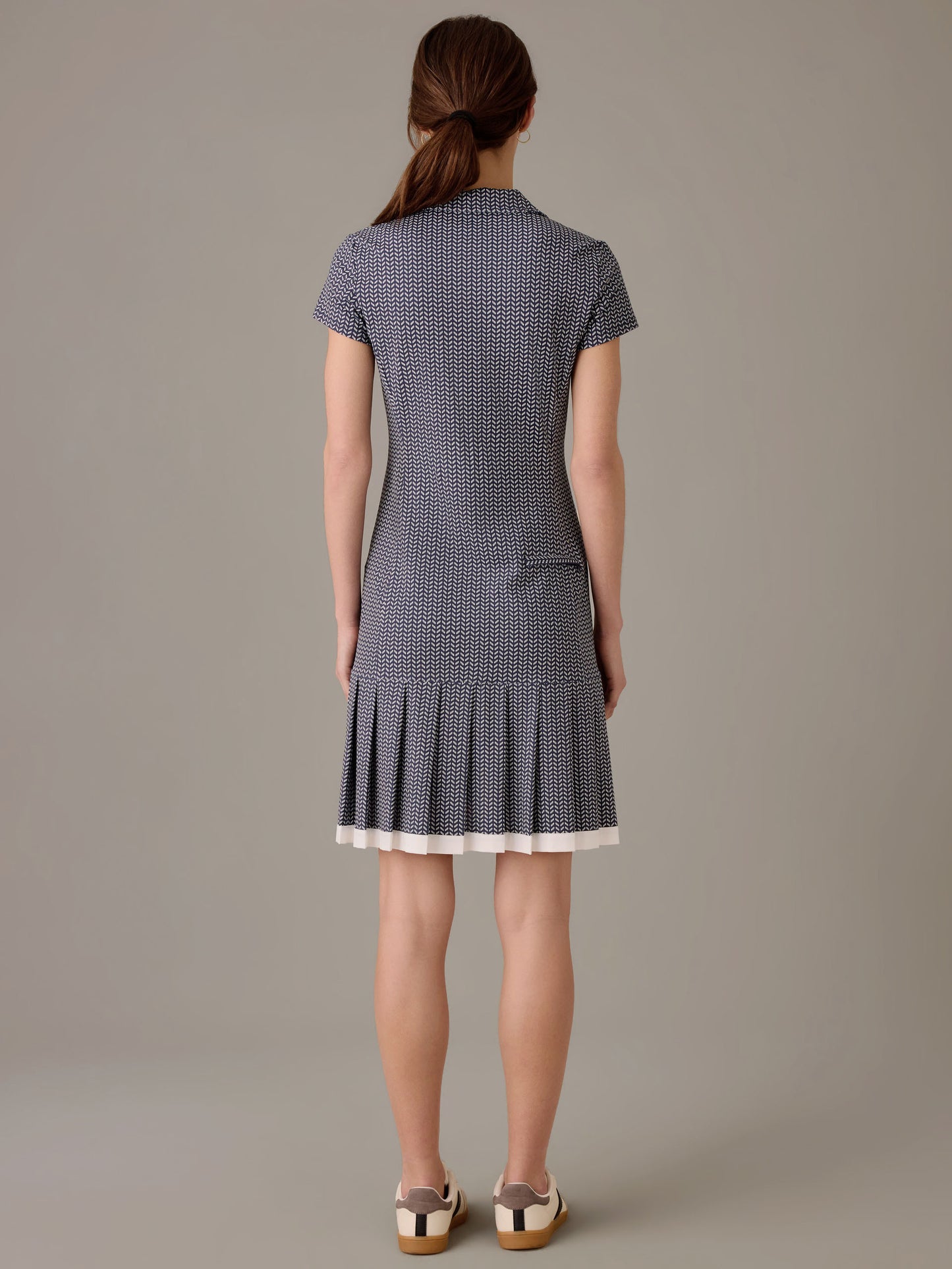 A woman wearing the Dorte Dress in Vine by J.McLaughlin, featuring a fitted silhouette with short sleeves and a pleated hem, styled with casual shoes.