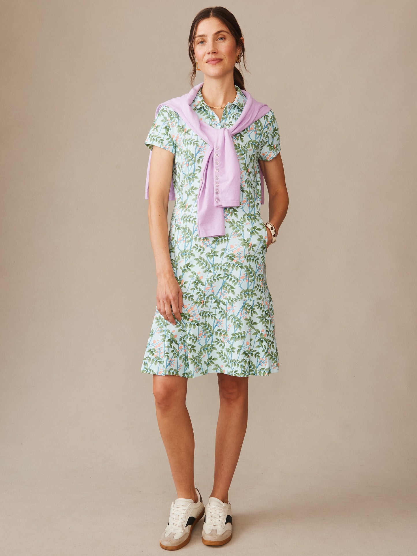 Woman wearing a Dorte Dress in Neo Blooming Vines by J.McLaughlin, featuring a floral print dress paired with a lightweight lavender sweater draped over shoulders, showcasing effortlessly stylish, enduring designs and innovative fabrics from a destination for defining style. Life, Well-Lived.