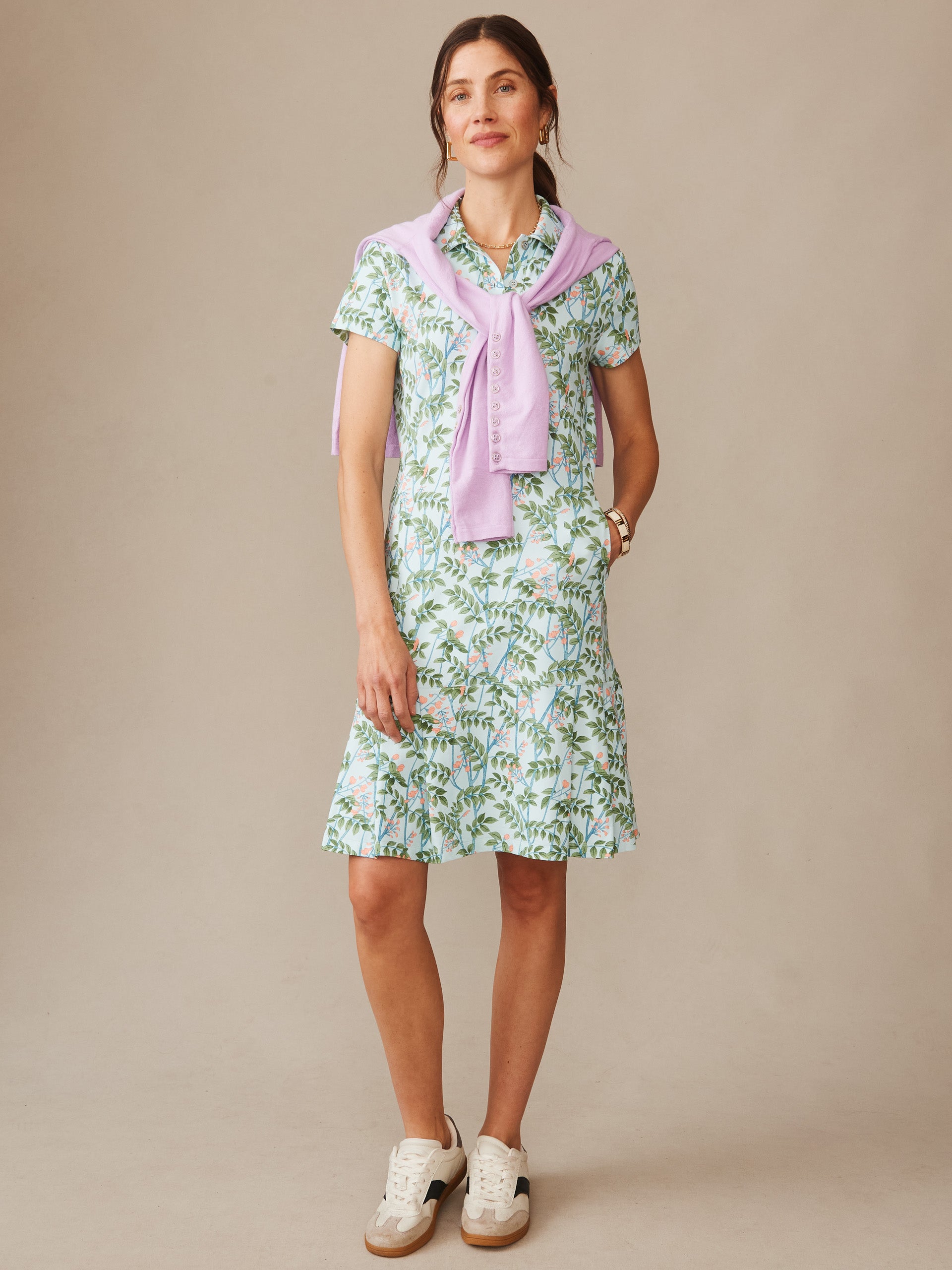 Woman wearing a Dorte Dress in Neo Blooming Vines by J.McLaughlin, featuring a floral print dress paired with a lightweight lavender sweater draped over shoulders, showcasing effortlessly stylish, enduring designs and innovative fabrics from a destination for defining style. Life, Well-Lived.